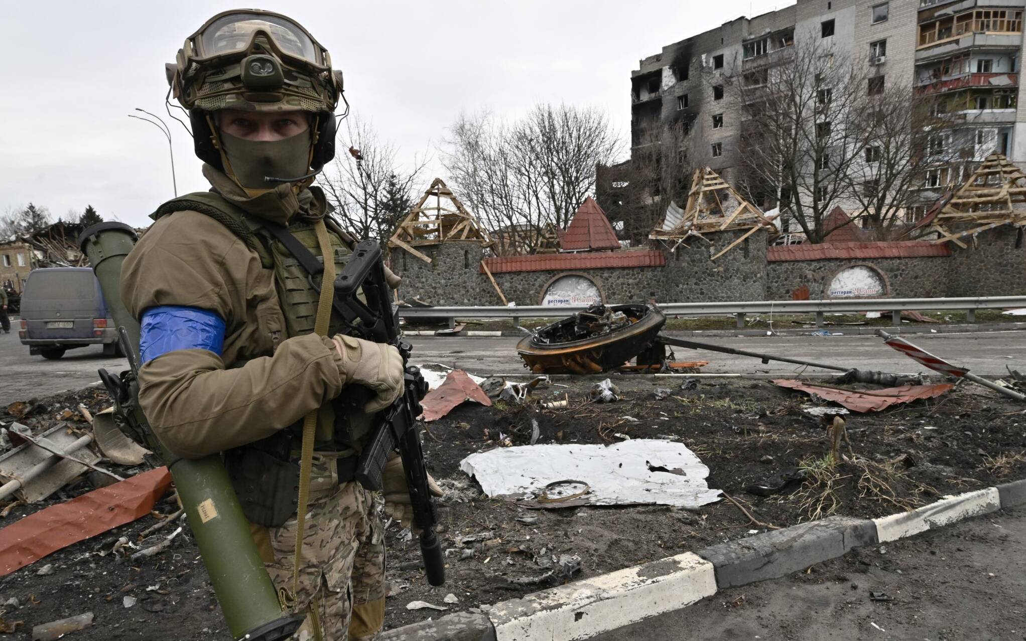 A Ukrainian serviceman stands guard on a street beside a damaged building in the town of Borodianka, northwest of Kyiv, on April 6, 2022, during Russia's military invasion launched on Ukraine. - The Russian retreat last week has left clues of the battle waged to keep a grip on Borodianka, just 50 kilometres (30 miles) north-west of the Ukrainian capital Kyiv. (Photo by Genya SAVILOV / AFP)