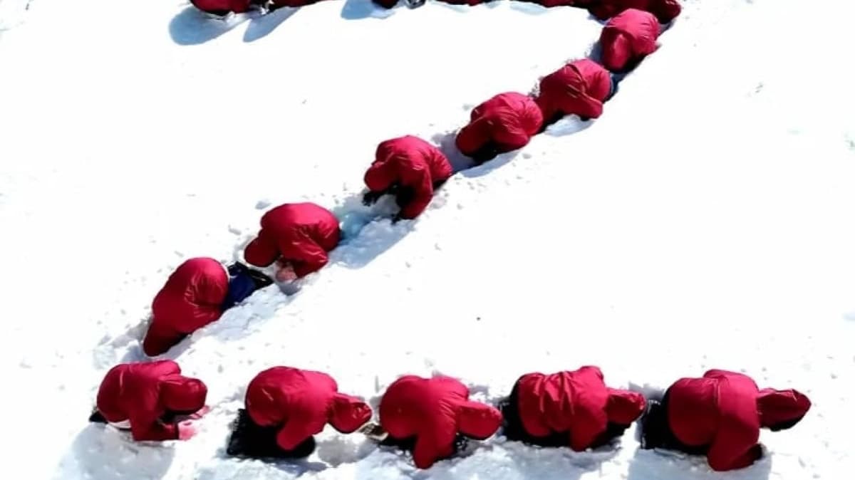 Ludzie w czerwonych kurtkach w śniegu ustawili się w literę Z