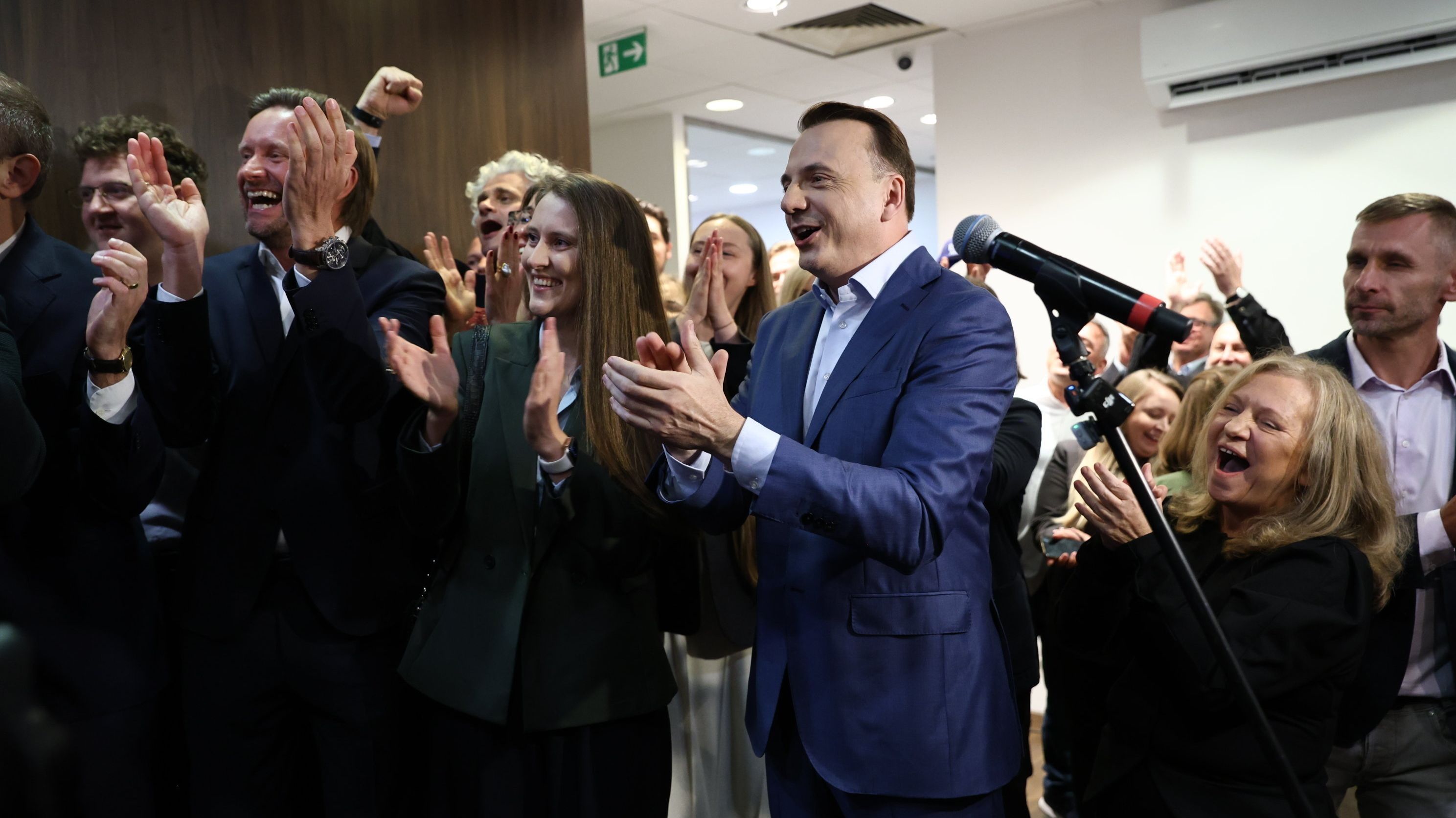 Gibała w niebieskiej marynarce bije brawo, wokół osoby z jego sztabu