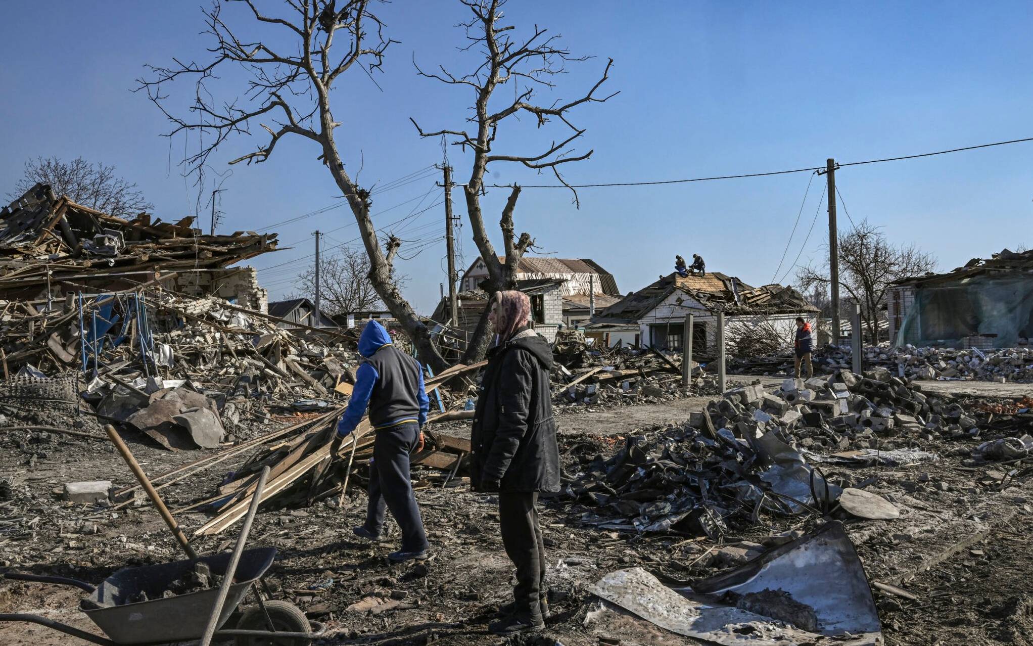 People clean up the debris from destroyed houses after bombardments in the village of Krasylivka, east of Kyiv, on March 20, 2022, as Russian forces try to encircle the Ukranian capital. - The war in Ukraine, which Russian President Vladimir Putin launched on February 24 to stamp out the pro-Western leanings in the ex-Soviet country, has sparked the fastest growing refugee crisis in Europe since World War II, felled Russia-West relations to Cold War-era lows, and is wreaking havoc in the world economy still recovering from the coronavirus pandemic. (Photo by Aris Messinis / AFP)