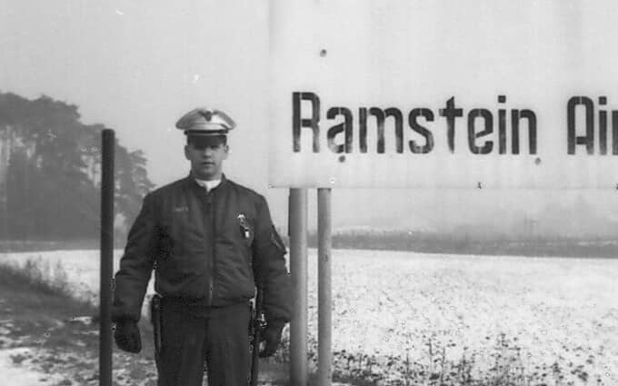 Mężczyzna stoi przy tablicy z napisem Ramstein USA Air Base