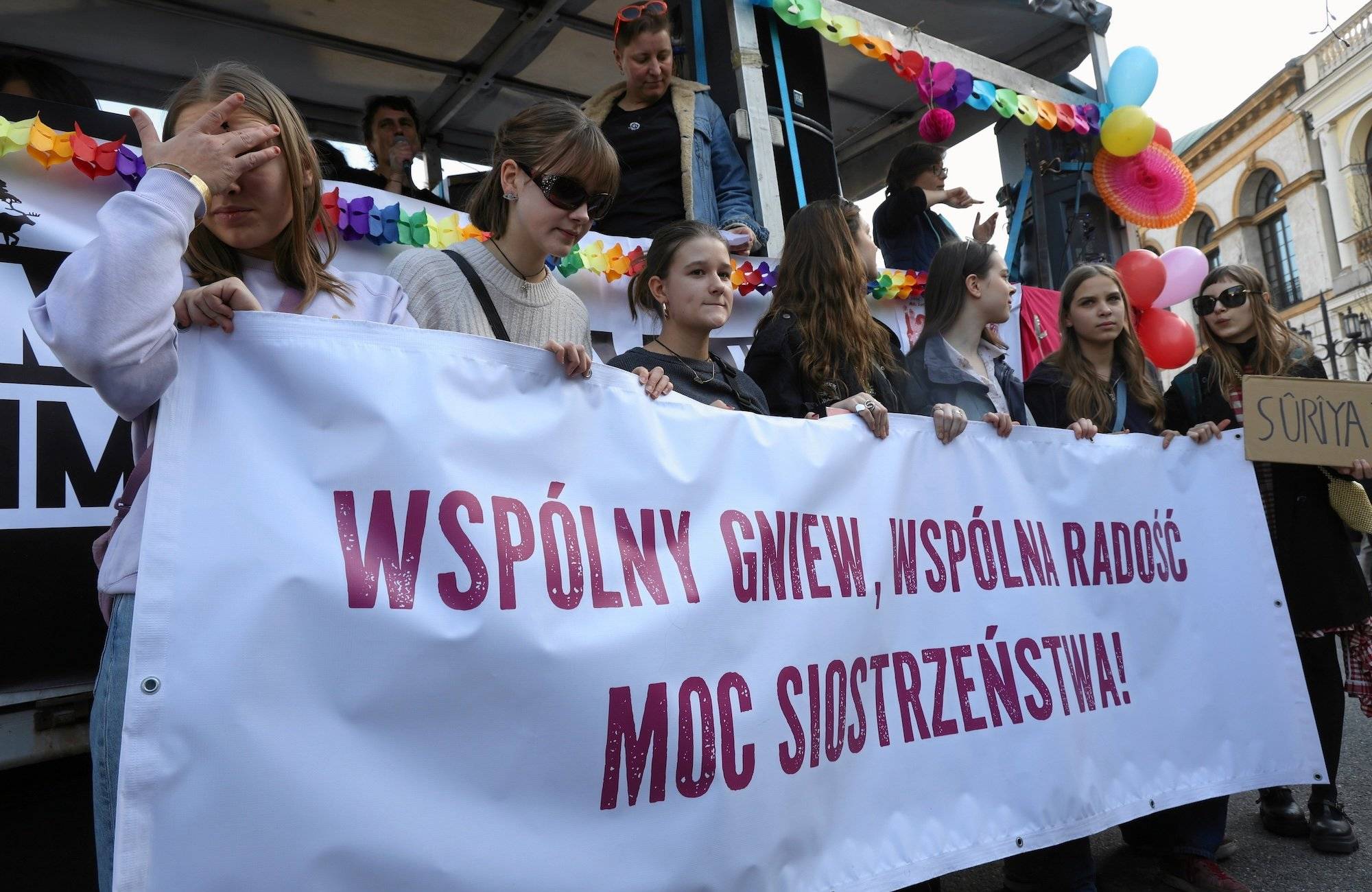 Dziewczyny niosące duży transparent z hasłem tegorocznej manify
