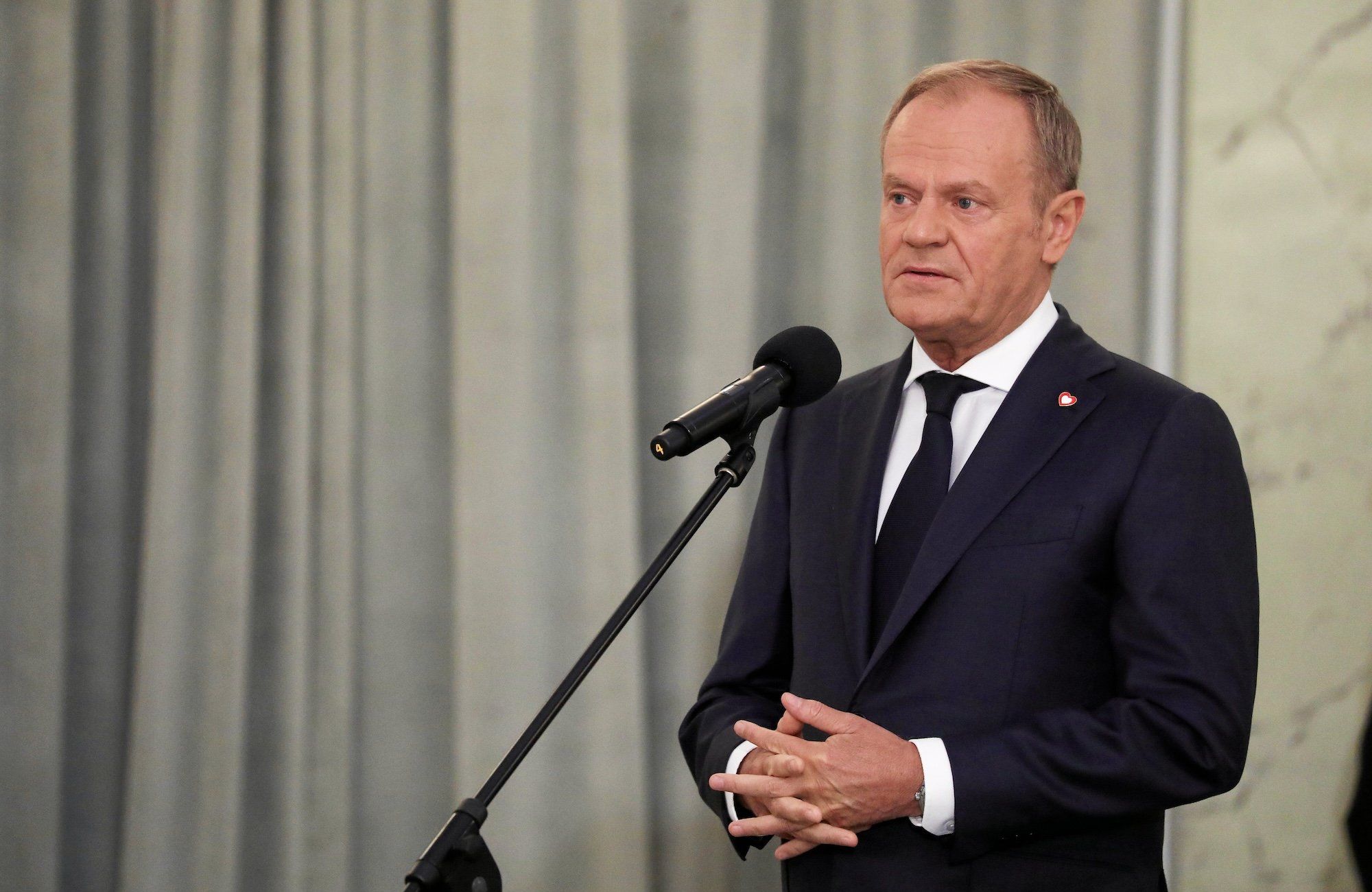 Donald Tusk podczas konferencji prasowej, przemawia do mikrofonu.