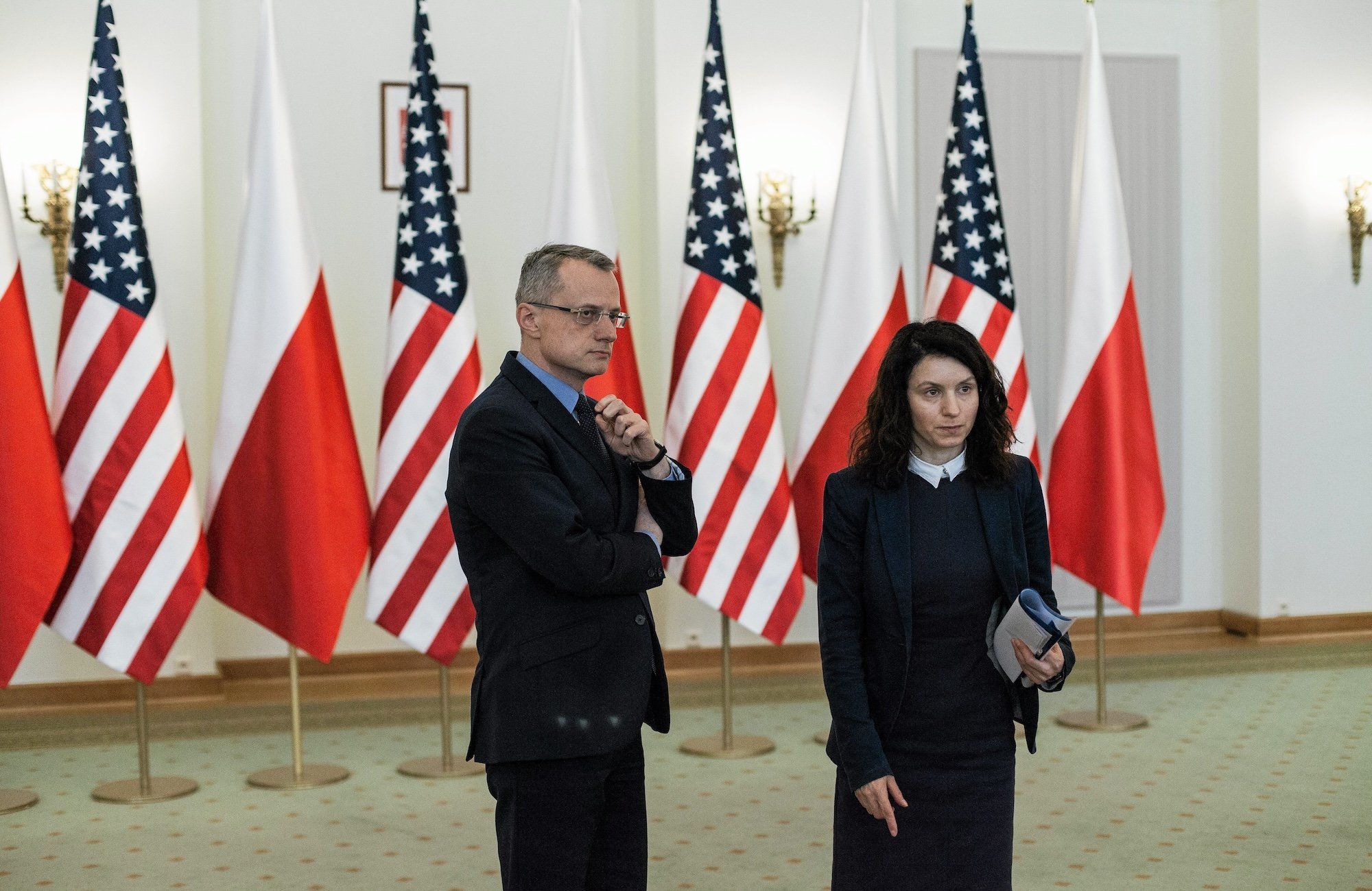 Marek Magierowski i nieznana kobieta stoją w pałacu prezydenckim na ple flag USA i Polski