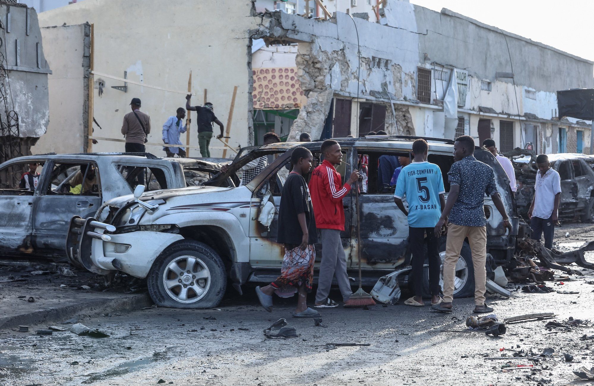 Mężczyźni stoją wokół z samochodu zniszczonego w stolicy Somalii, Mogadiszu
