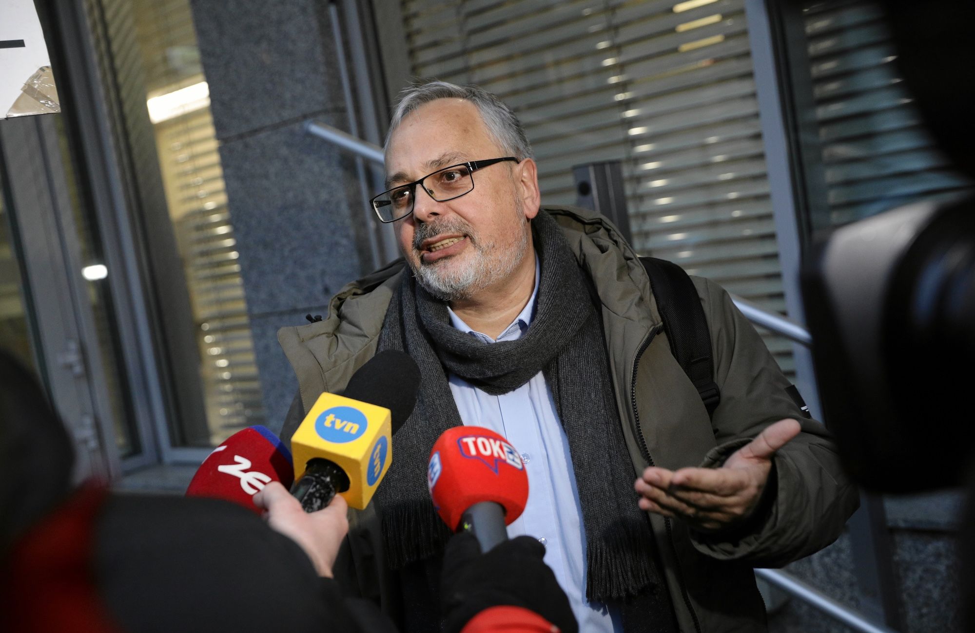 Profesor Ryszard Balicki przemawia do dziennikarzy pod budynkiem PKW. To siwy mężczyzna po pięćdziesiątce z krótkim siwym zarostem. Na twarzy ma okulary w ciemnych oprawkach. Ubrany w oliwkowozieloną kurtkę, niebieską koszulę i szalik.