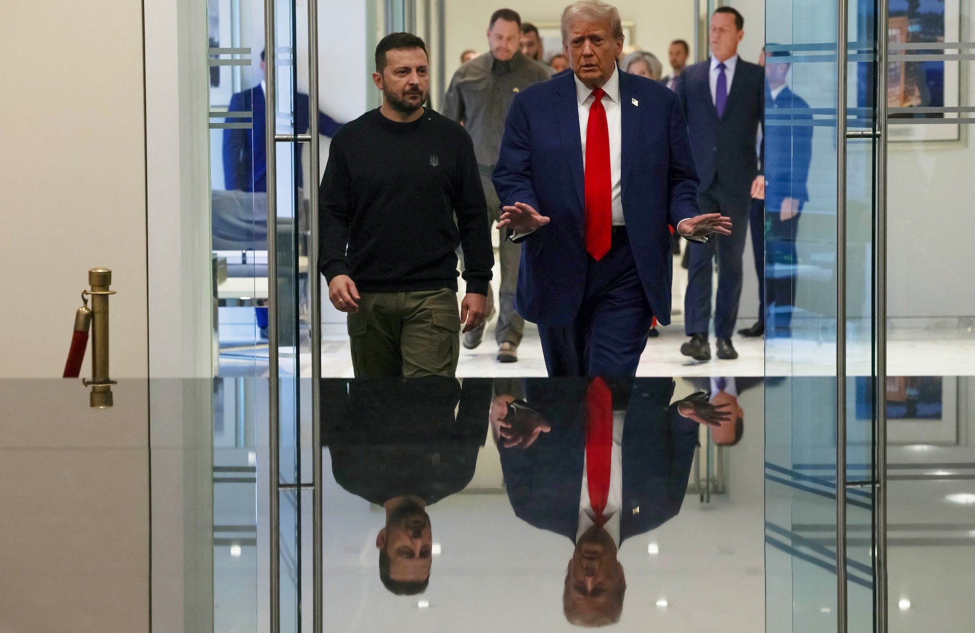 Wołodymyr Zełenski i Donald Trump podczas spotkania w Waszyngtonie. Zełenski ubrany w ciemnozieloną bluzę i spodnie, Trump w granatowym garniturze i czerwonym krawacie
