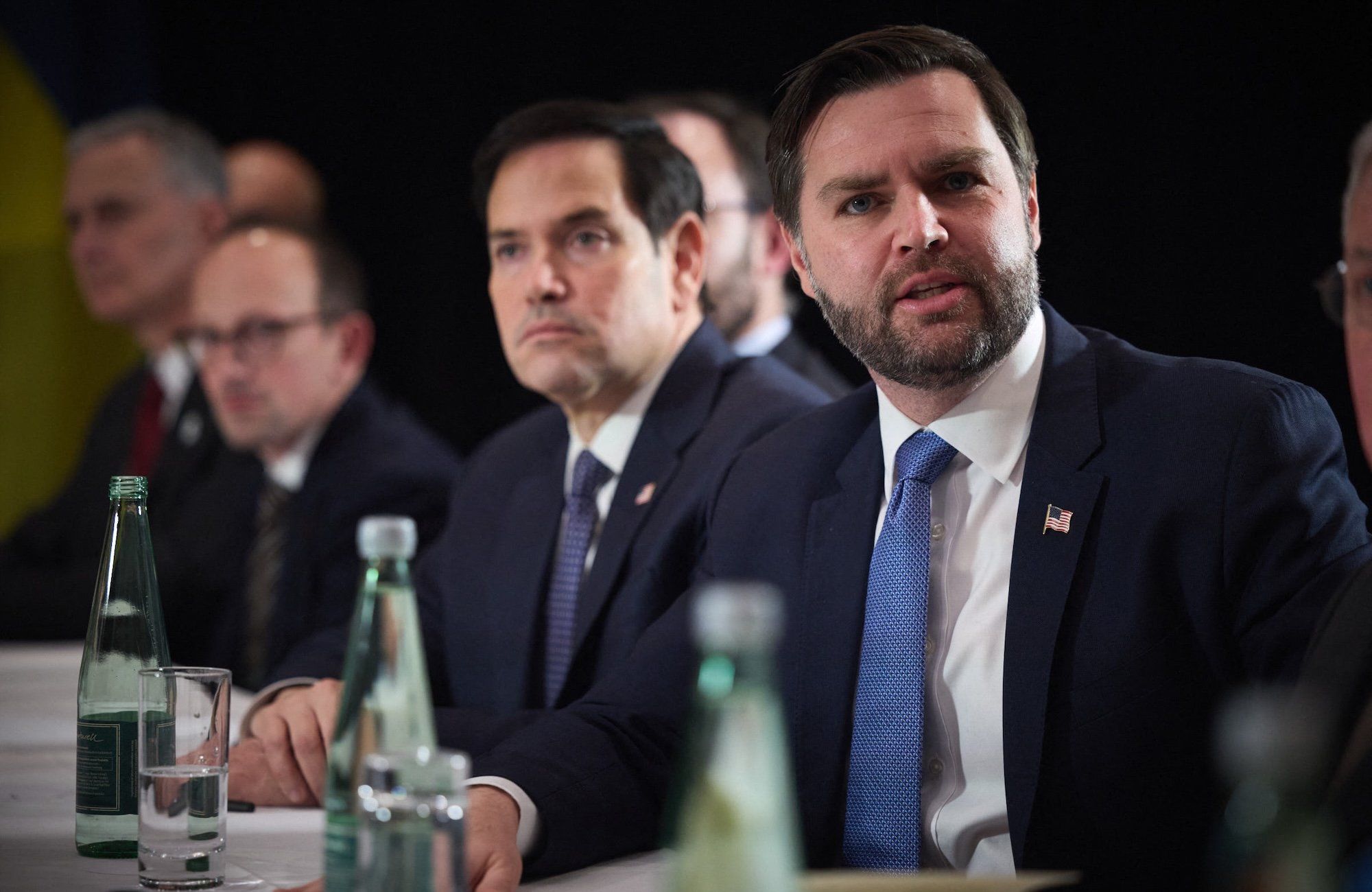 Wiceprezydent USA J.D. Vance a za nim sekretarz stanu USA Marco Rubio. Siedzą za stołem podczas spotkania dyplomatycznego, na stole szklane butelki z wodą