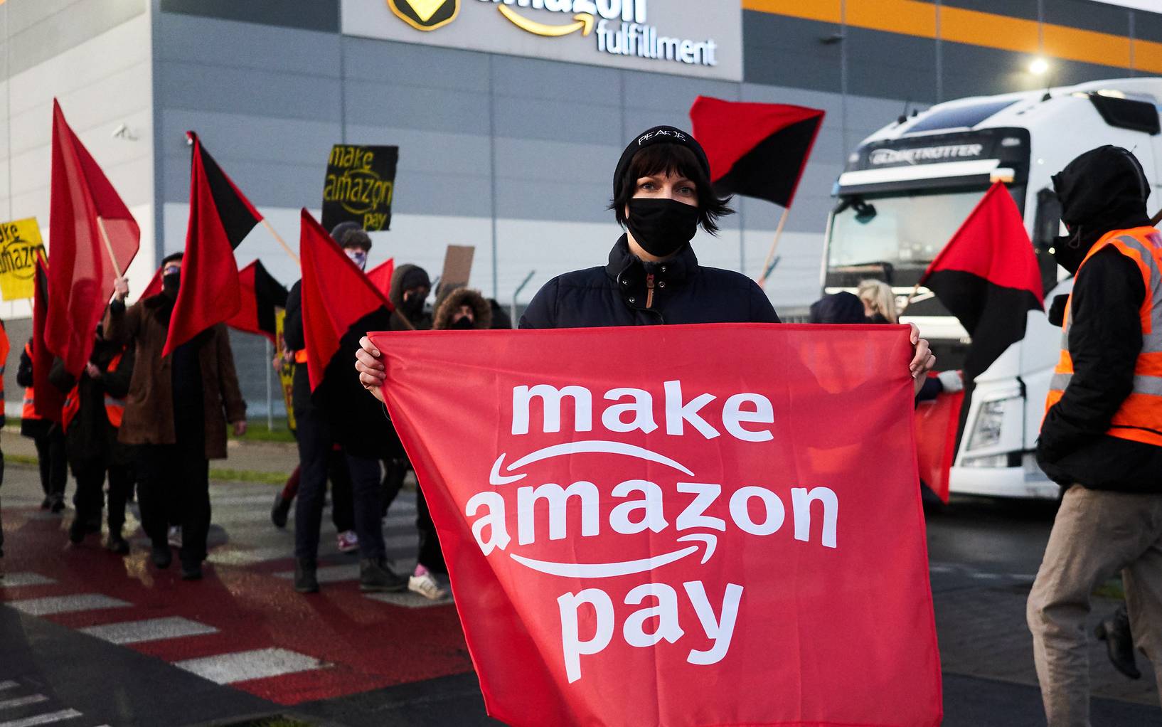 Grafika do artykułu "Niższe normy, wyższe pensje!" Protestujący zablokowali wjazd do magazynów Amazona