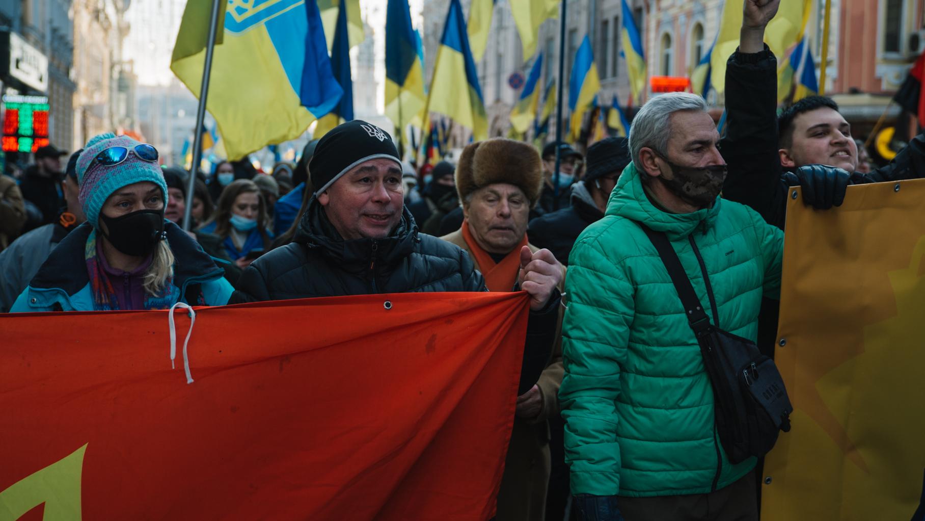 Ludzie w zimowych kurtkach z transparentami i flagami