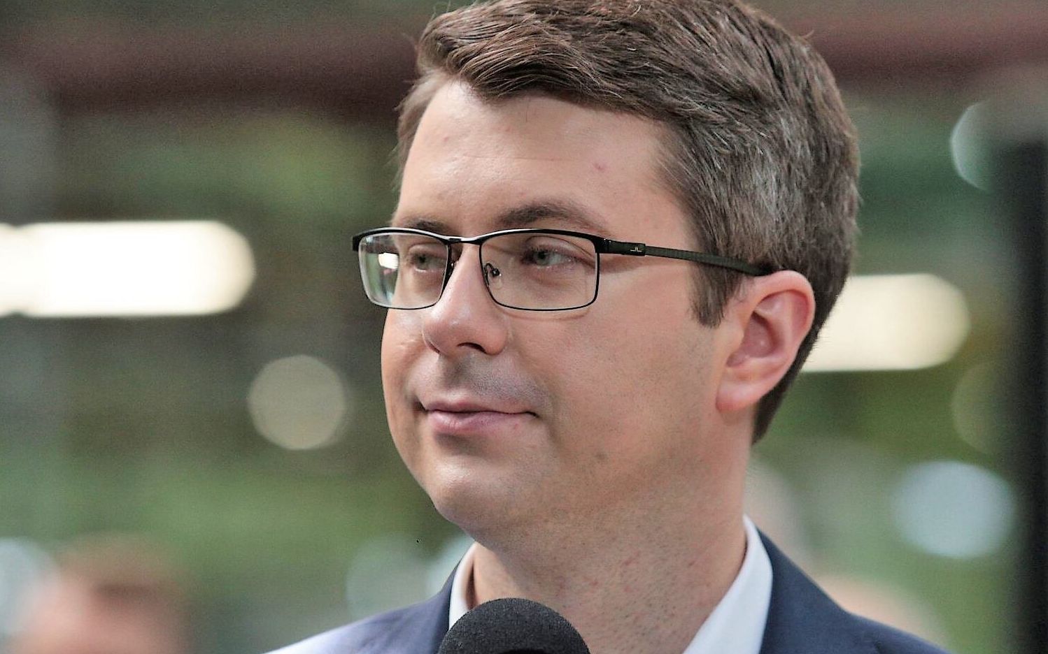 Piotr Müller, rzecznik rządu stoi przed mikrofonem