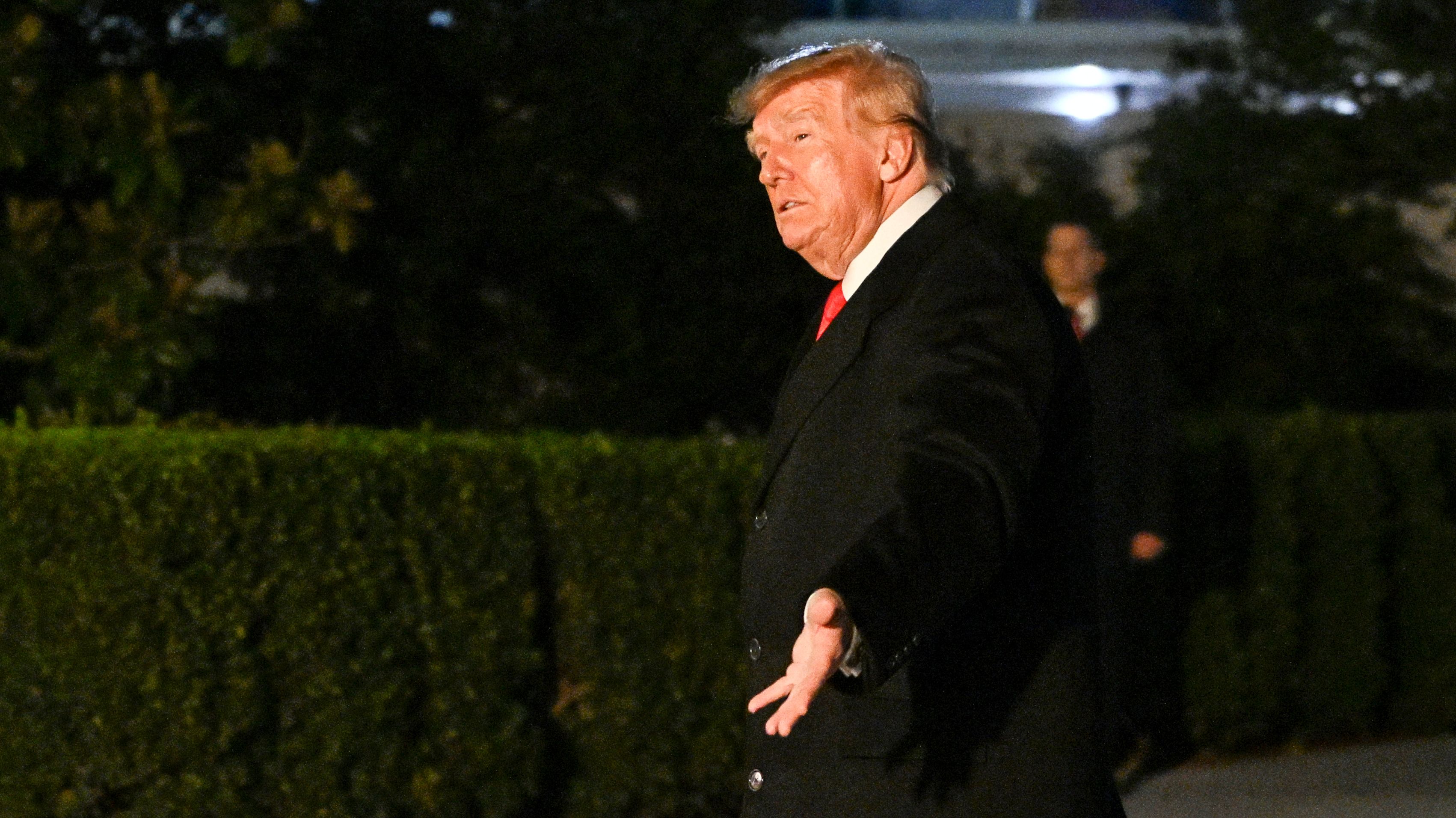 Trump rozkłada ręce. Zdjęcie zrobione w nocy.