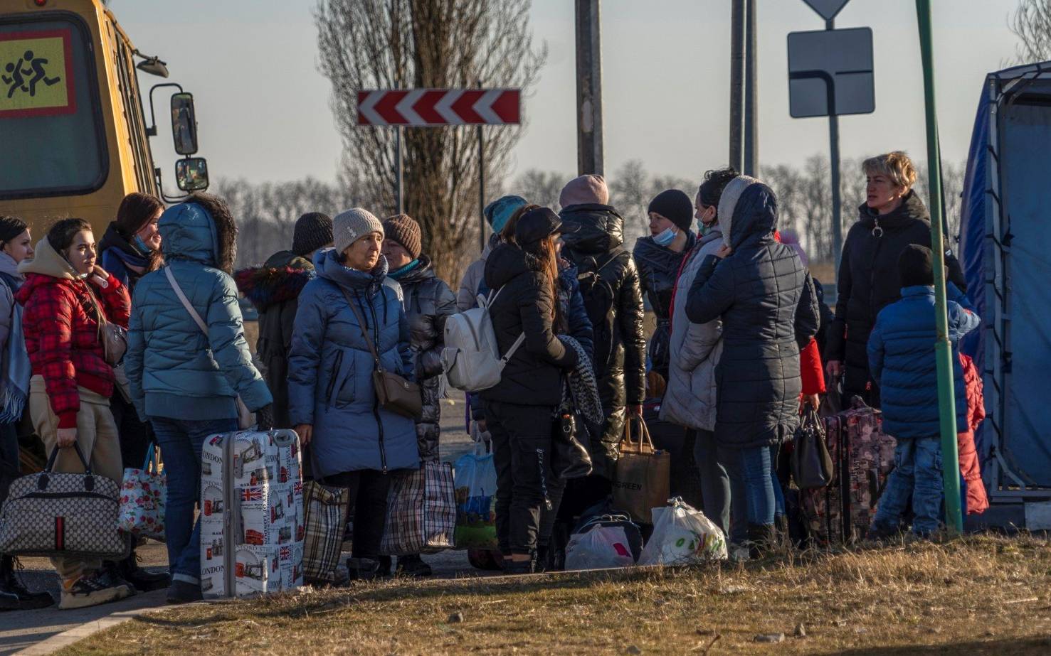 People evacuated from the self-proclaimed Donetsk People's Republic walk toward the Russian Emergency Ministry camp in the village of Veselo-Voznesenka on the Azov Sea coast, on February 19, 2022. - A Russian region bording Ukraine declared a state of emergency on February 19, 2022, citing growing numbers of people arriving from separatist-held regions in Ukraine after they received evacuation orders. (Photo by Andrey BORODULIN / AFP)