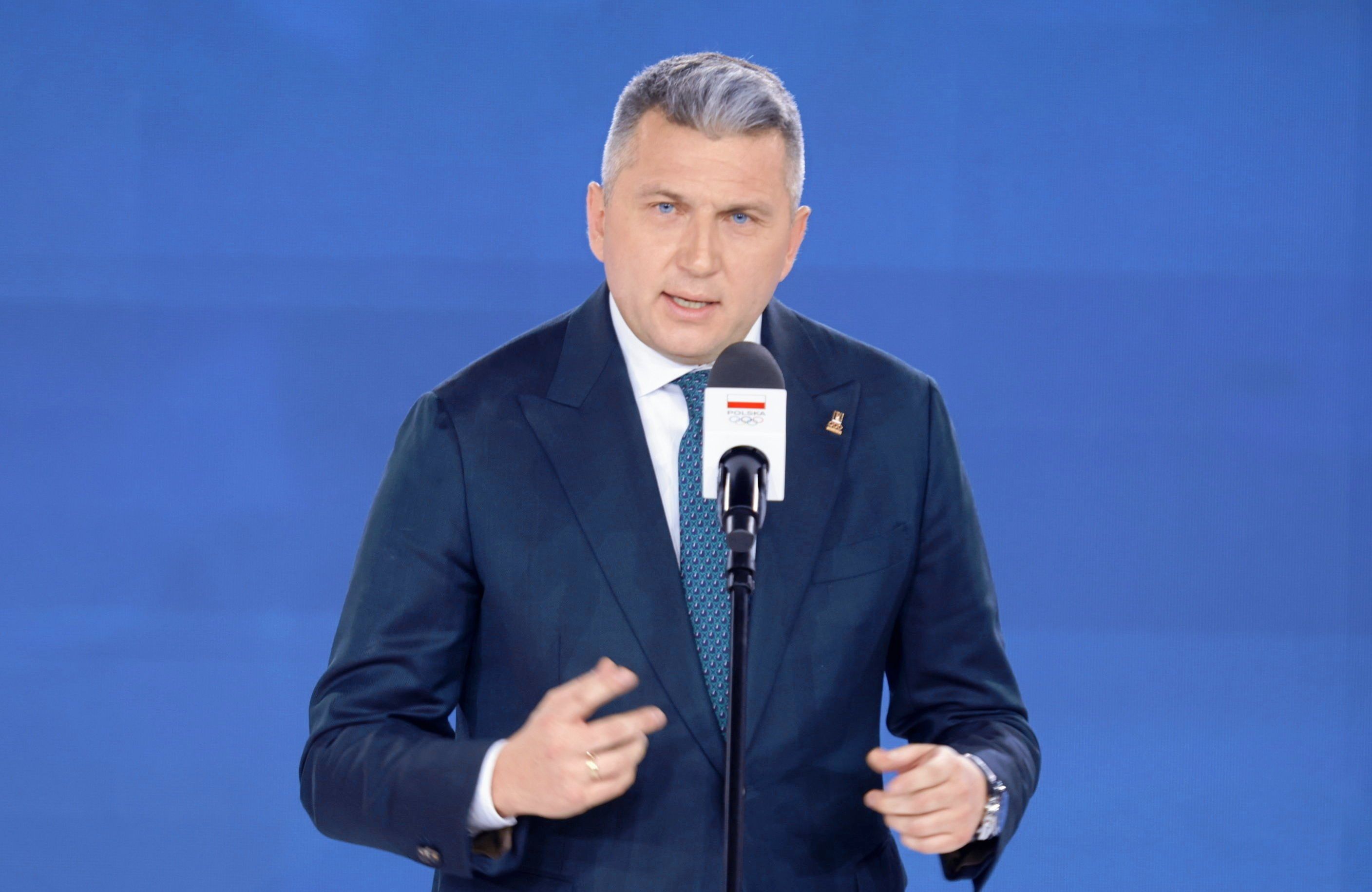 15.11.2024, Warszawa. Prezes PKOl Radosław Piesiewicz podczas wręczenia nagród medalistom olimpijskim z Paryża. Na zdjęciu mężczyzna w średnim wieku w granatowym garniturze przemawia do mikrofonu.