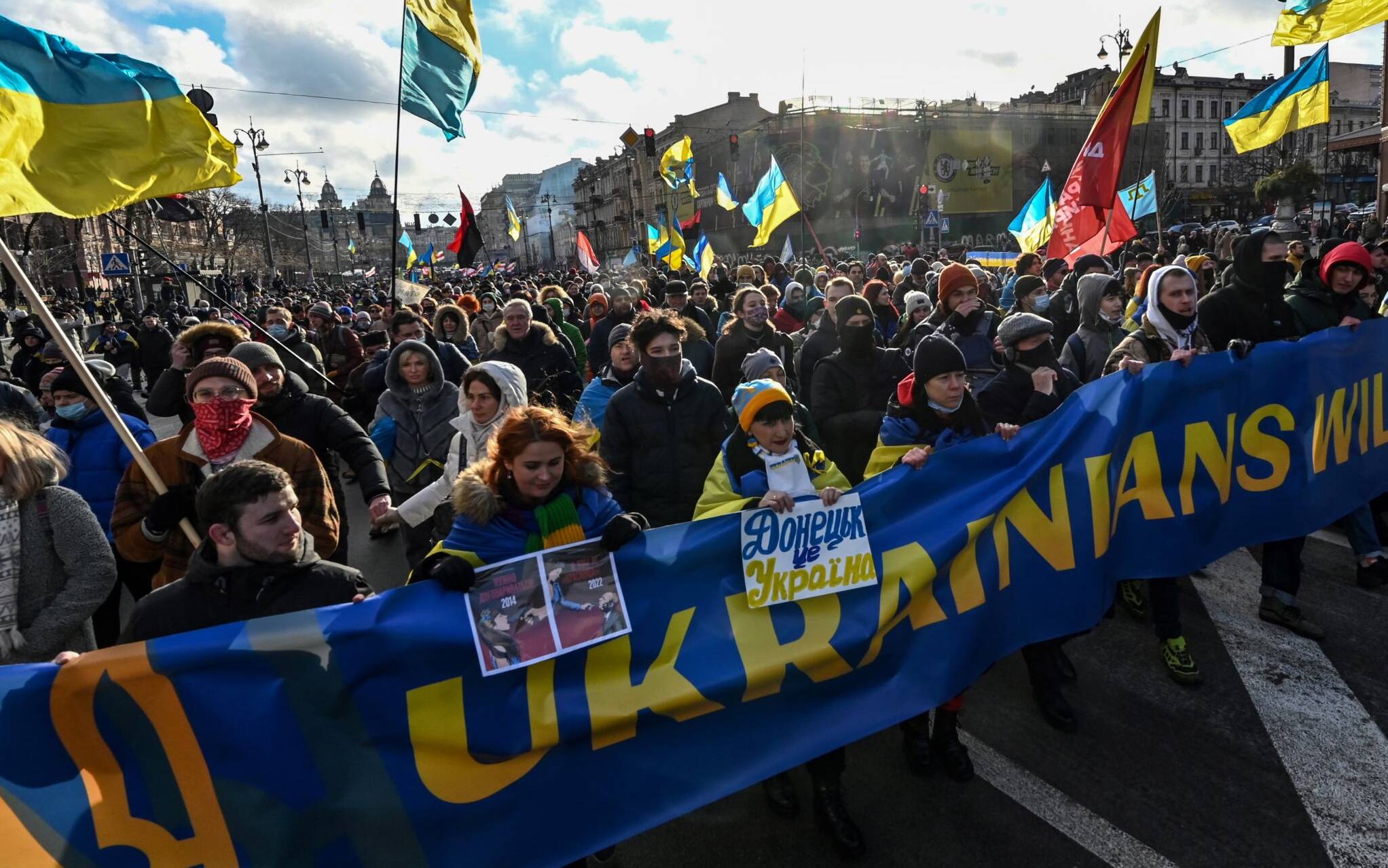Demonstrators shout slogans as they march behind a banner which reads "Ukrainians will resist" in the colours of the national flag during a rally in Kyiv on February 12, 2022, held to show unity amid US warnings of an imminent Russian invasion. - Ukrainian President Volodymyr Zelensky said that warnings of an imminent Russian attack on his country were stoking "panic" and demanded to see firm proof of a planned invasion. (Photo by Sergei SUPINSKY / AFP)