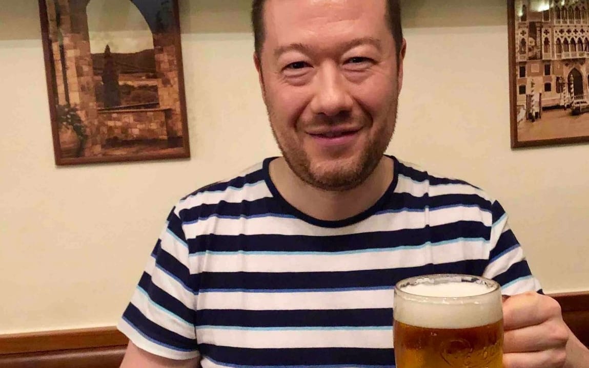 Mężczyzna w pasiatym polo z kuflem piwa w ręku