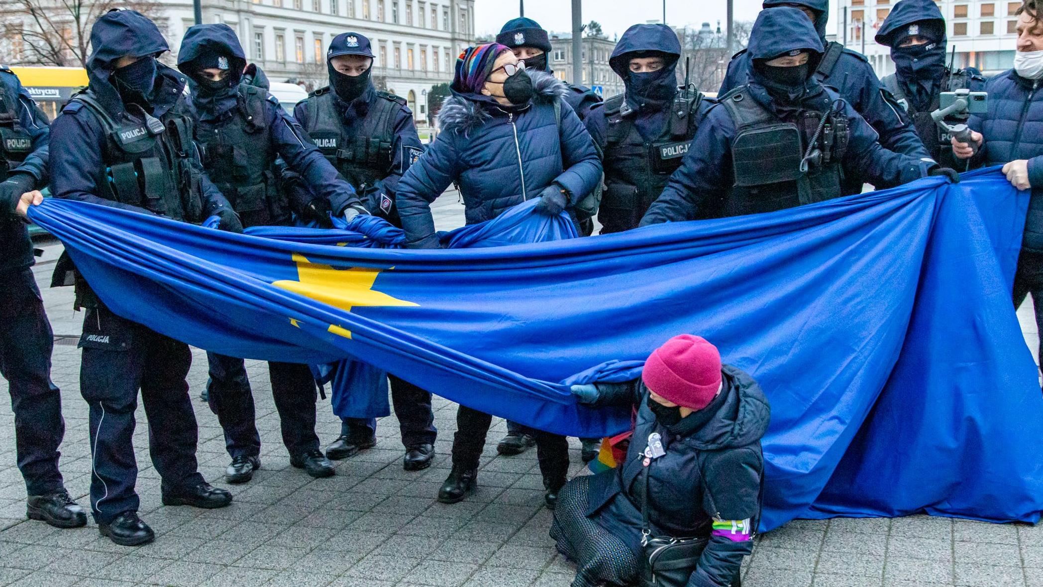 Rząd policjantów i kobieta broniąca flagi Unii