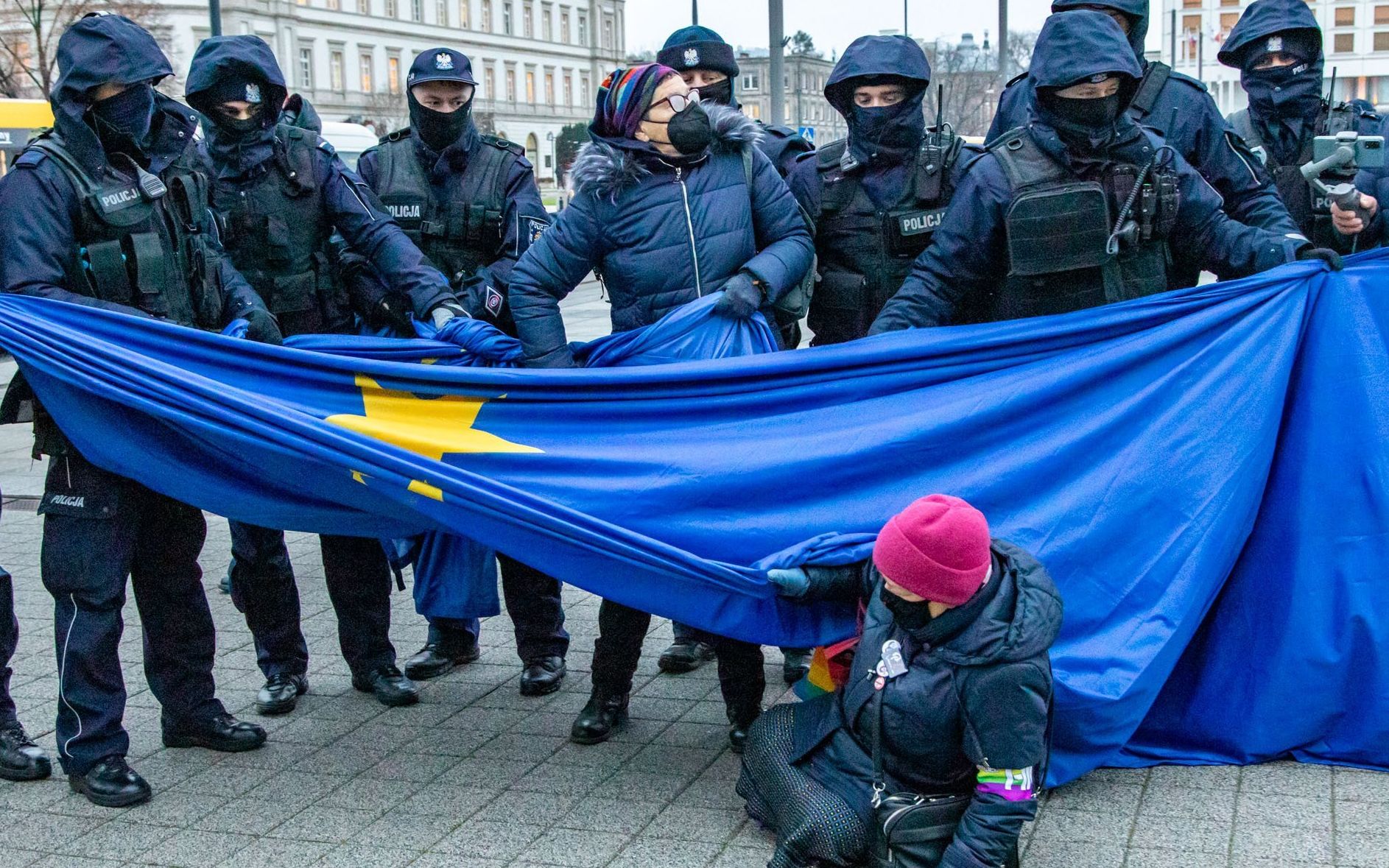 Rząd policjantów i kobieta broniąca flagi Unii