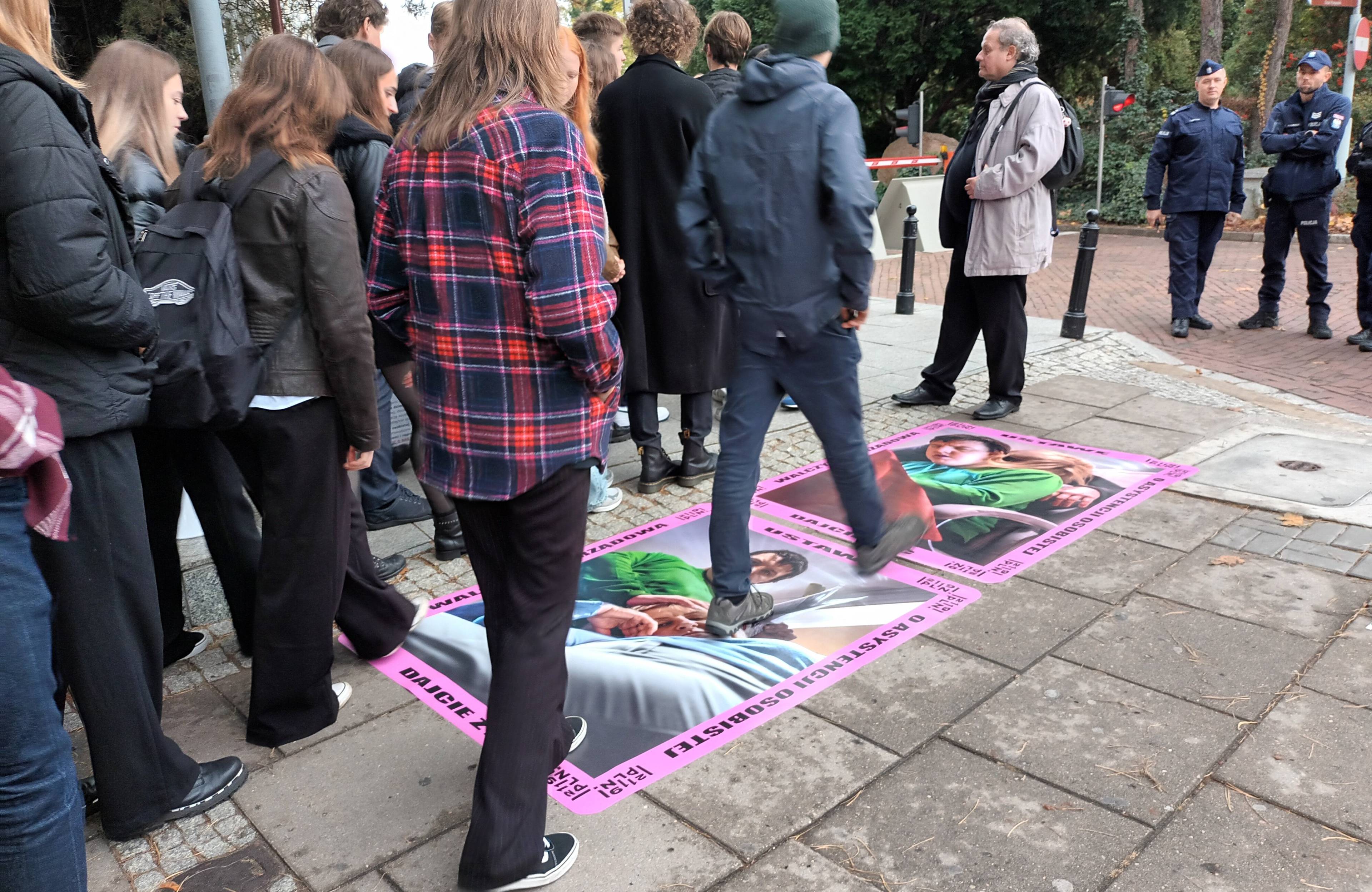 Młodzi ludzie przechodzą po plakatach na chodniku