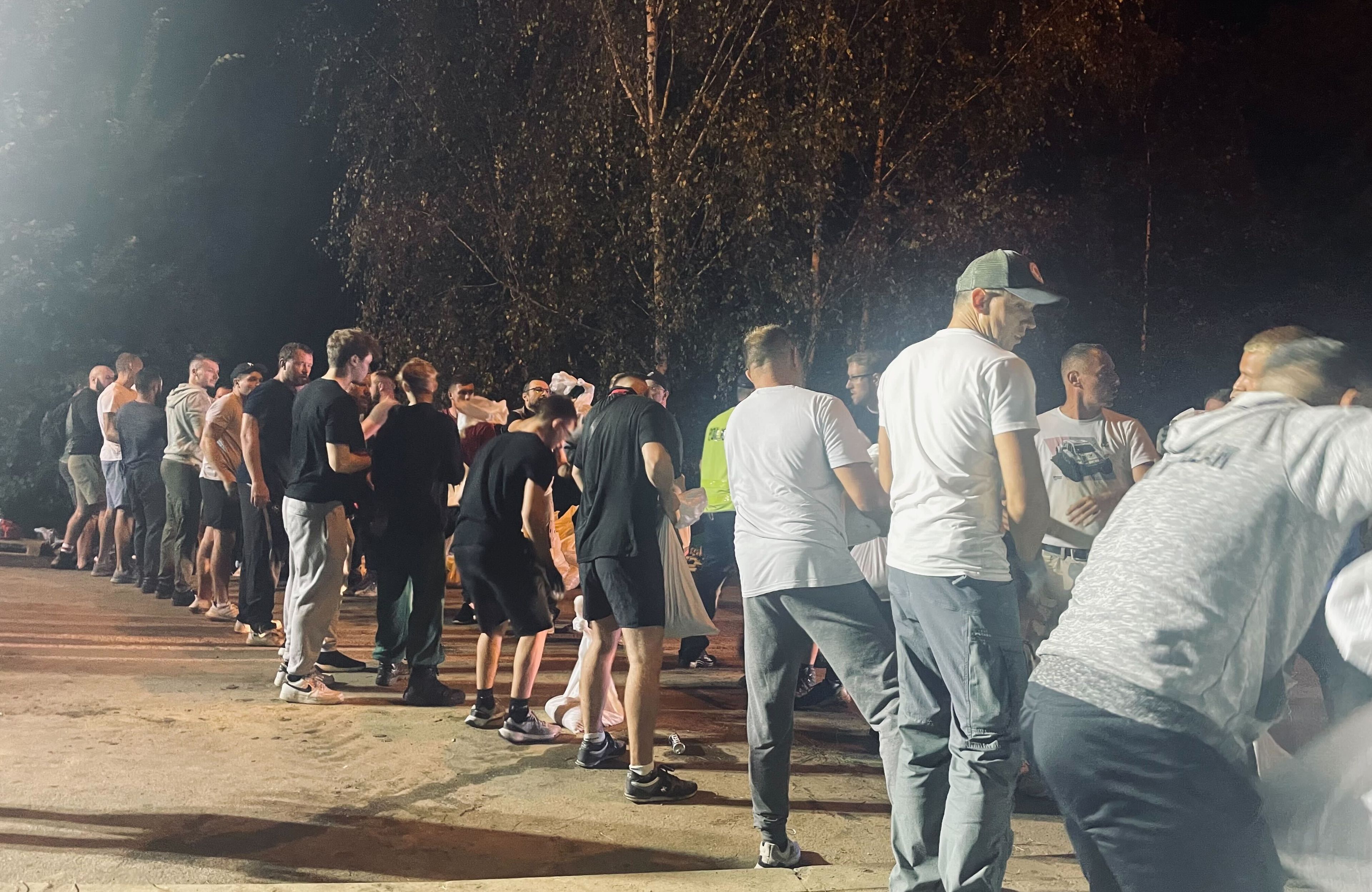 Ludzie układają worki z piaskiem