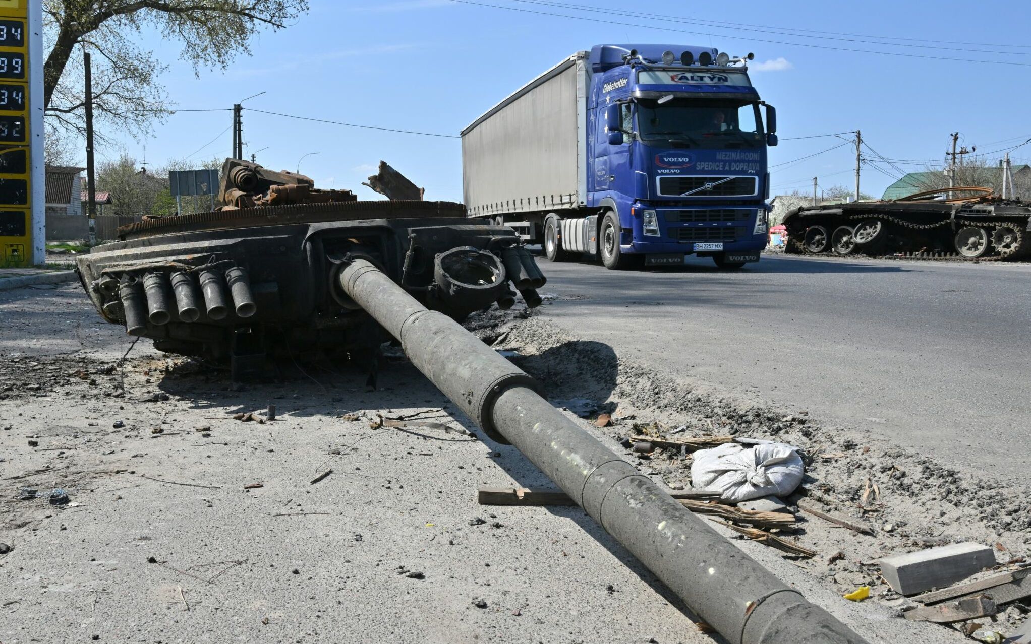 A truck drive past a wreckage of a Russian tank next to a destroyed petrol station in Skybyn village, northeastern Ukrainian capital of Kyiv on May 2, 2022. - The snaking queues of cars that returned to many Ukrainian roads last week showcase the success of Russia's seeming effort to inflict as much pain on its western neighbour as possible. (Photo by Sergei SUPINSKY / AFP)