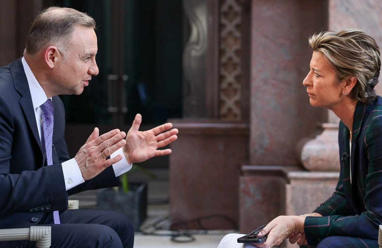 Prezydent Duda siedzi naprzeciw dziennikarki CNN i mówi gestykulując