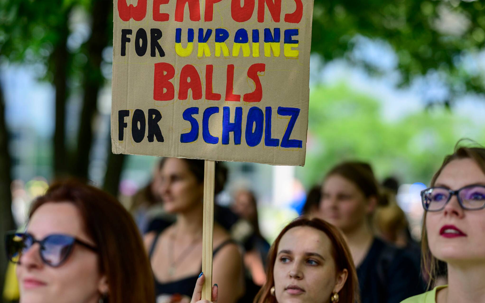 A woman displays a placard reading 'Weapons for Ukraine - balls for Scholz' during a demonstration to thank Germany for its support of Ukraine in Berlin on June 11, 2022. (Photo by John MACDOUGALL / AFP)