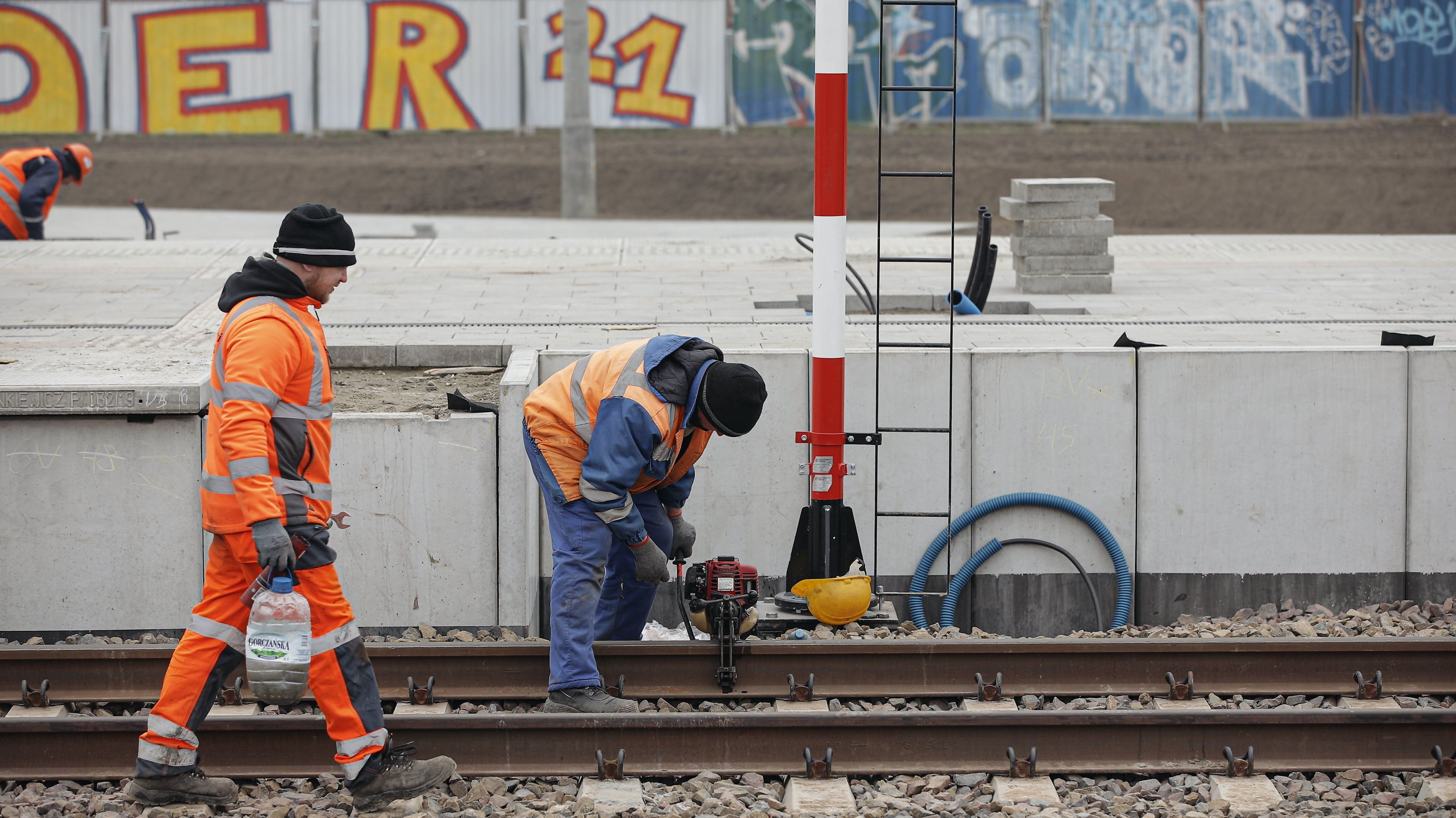 pracownicy na torach w pomarańczowych kamizelkach