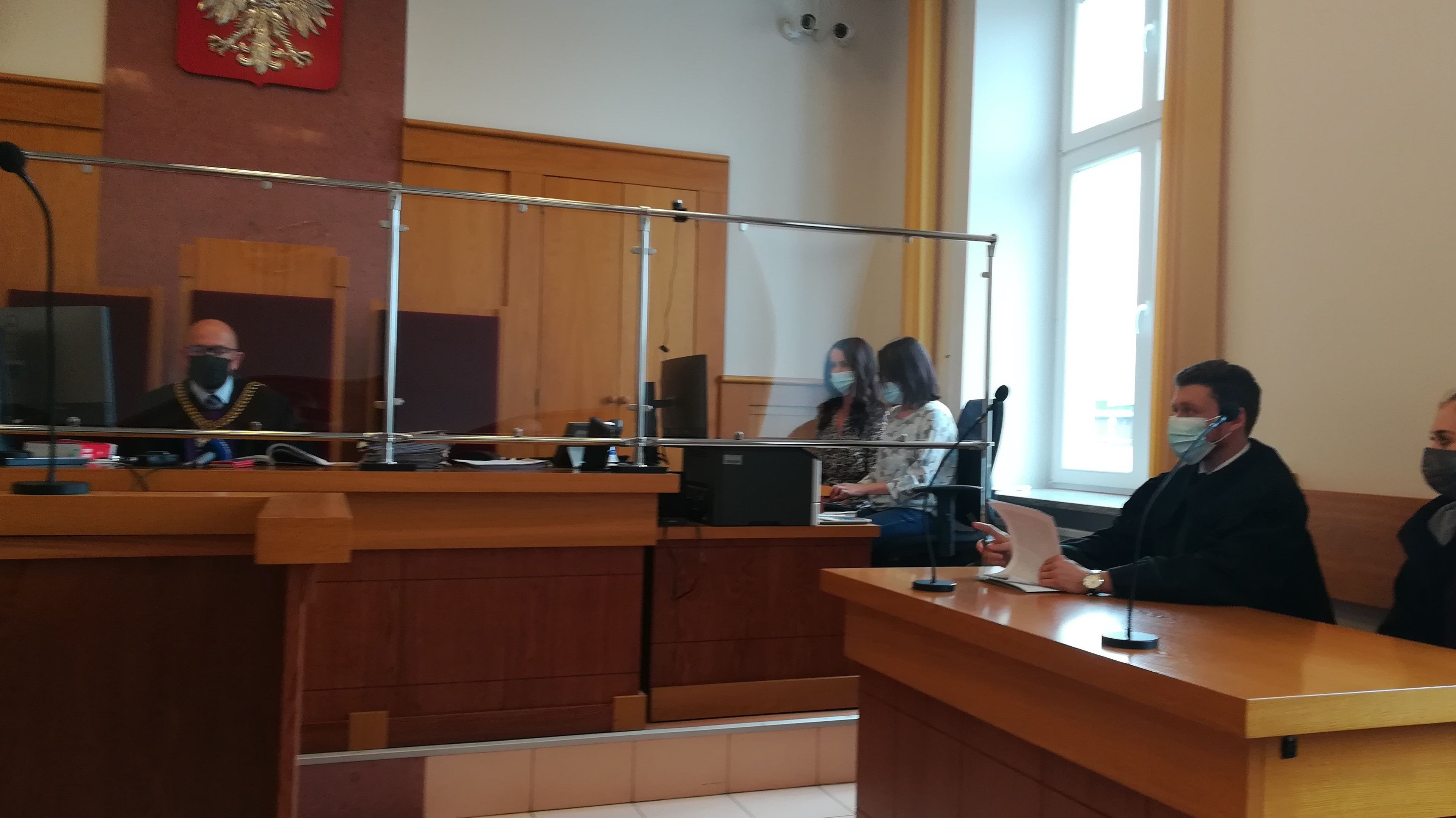 Sąd za szyba ochronną, obrońca w masce