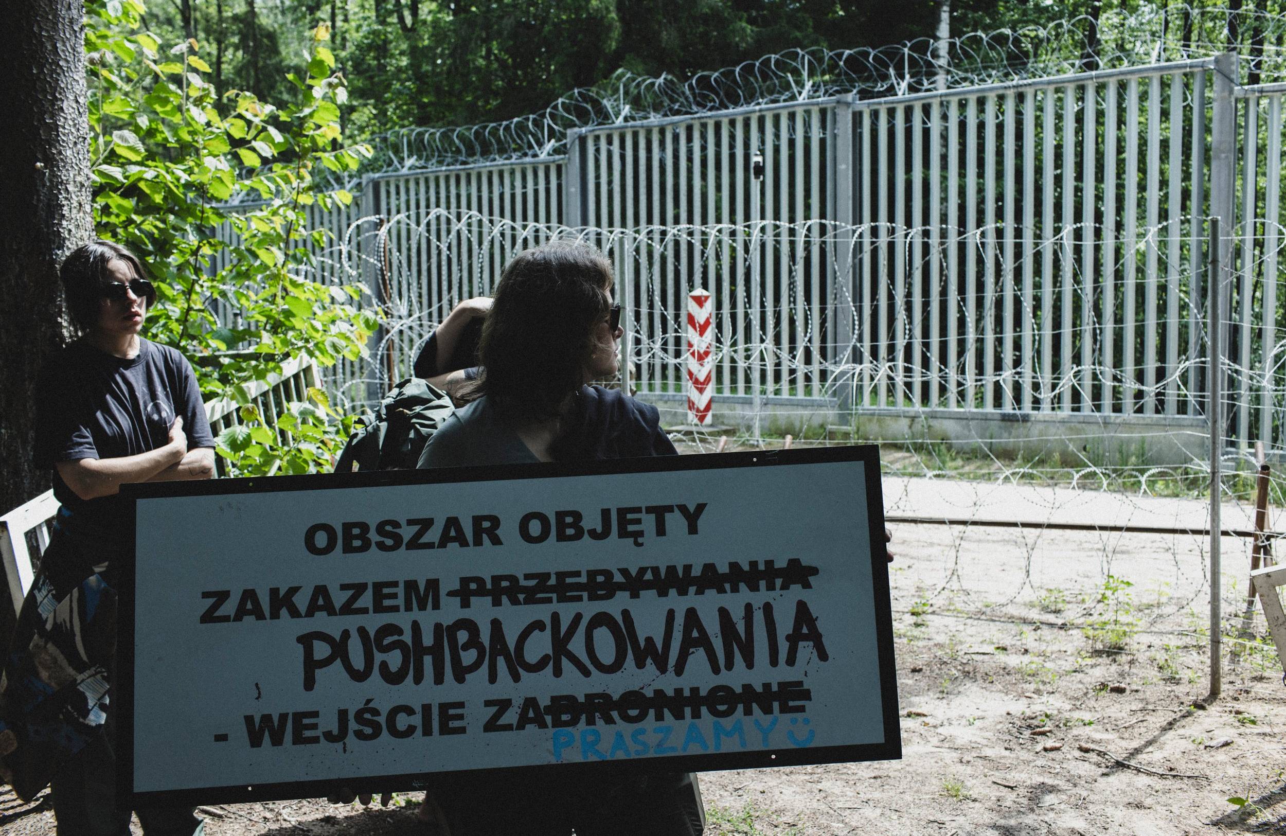kobieta trzymająca karton z napisem „Obszar objęty zakazem pushbackowania"