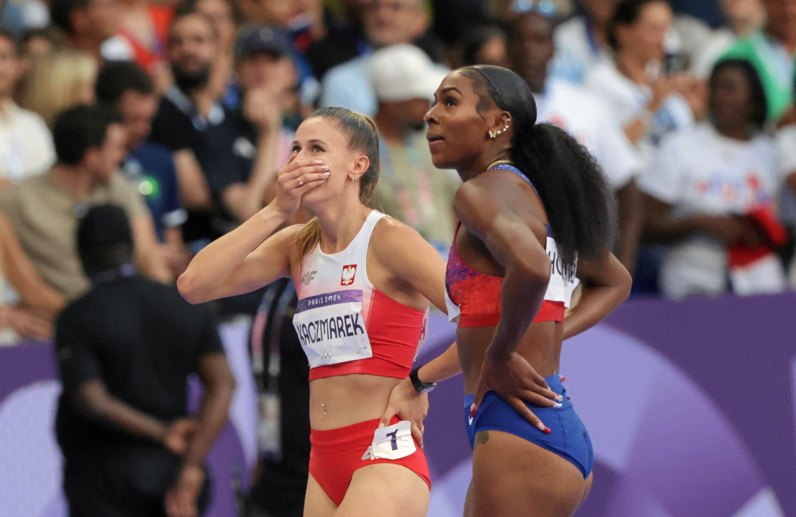 Czarna Amerykanka Alexis Holmes i biała Polka Natalia Kaczmarek patrzą na tablice wyników po finiszu biegu na 400 metrów na Igrzyskach Olimpijskich w Paryżu. Kaczmarek po zajęciu 2 miejsca zakrywa usta w geście zdziwienia. Ilustracja do tekstu "Igrzyska: osobne zawody dla białych i czarnych - czy to rasizm? [OPINIA]
