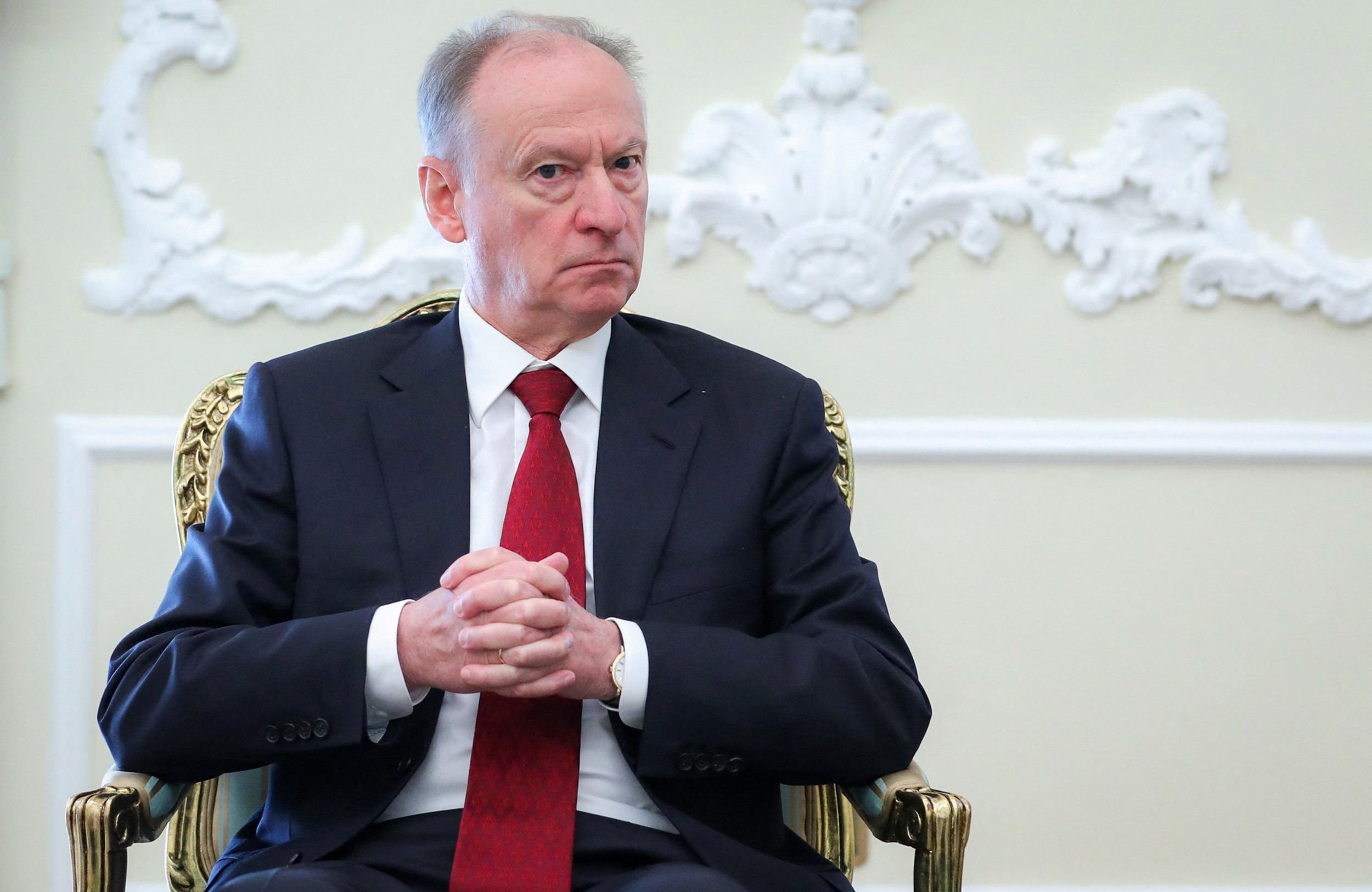 Nikołaj Patruszew w czerwonym krawacie siedzi na krześle