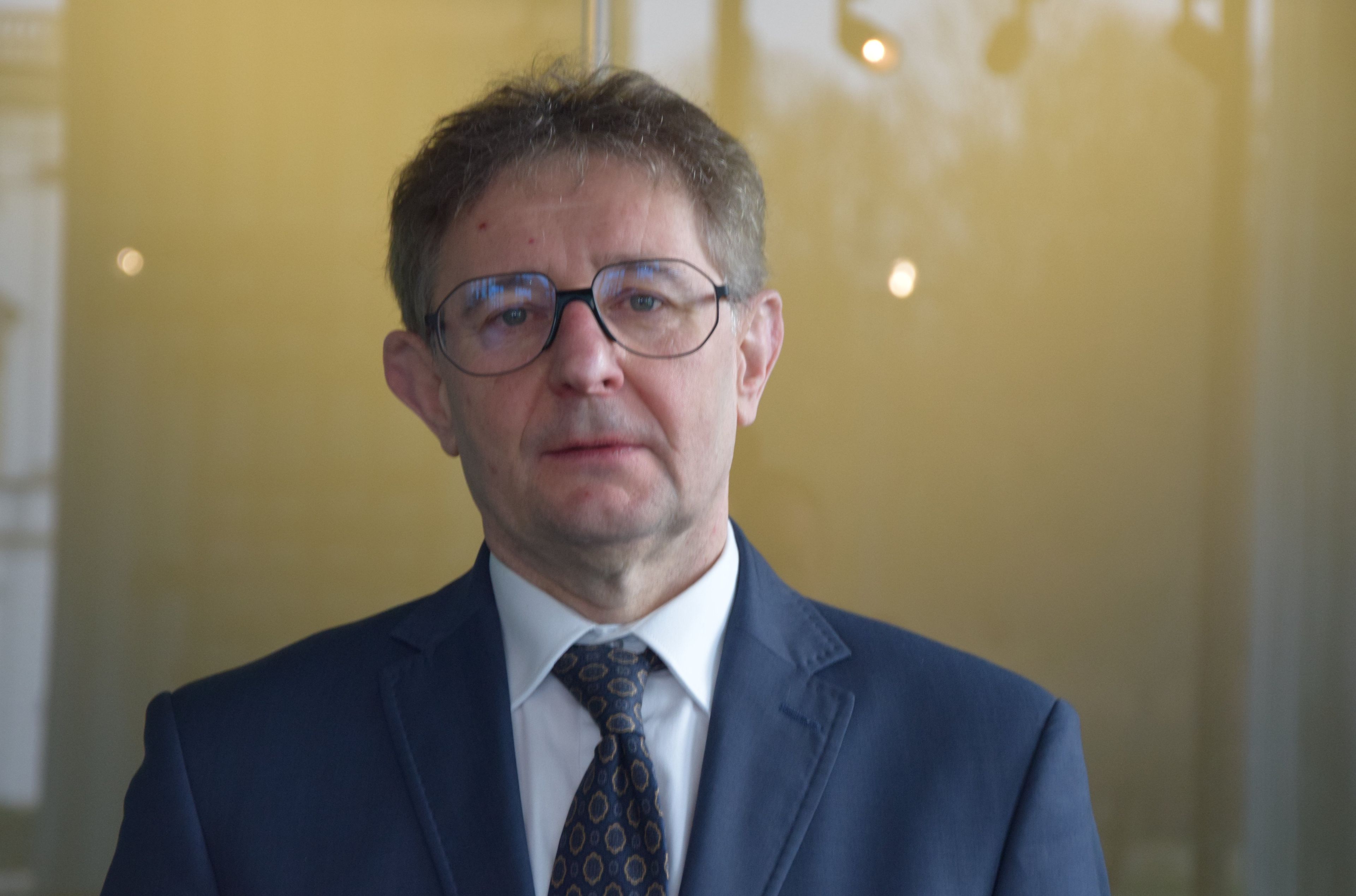 Mężczyzna w okularach, stoi, sędzia Tomasz Wojciechowski