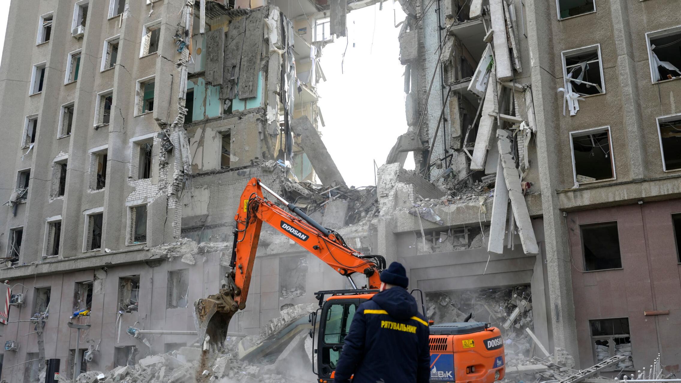 A worker watches an excavator clearing the rubble of a government building hit by Russian rockets in Mykolaiv on March 29, 2022. - A Russian strike battered the regional government building in the southern Ukrainian city of Mykolaiv, a key port under heavy assault for weeks, the regional governor said on March 29, 2022. Governor Vitaly Kim said that most people inside the building had not been injured but several civilians and soldiers were unaccounted for. (
