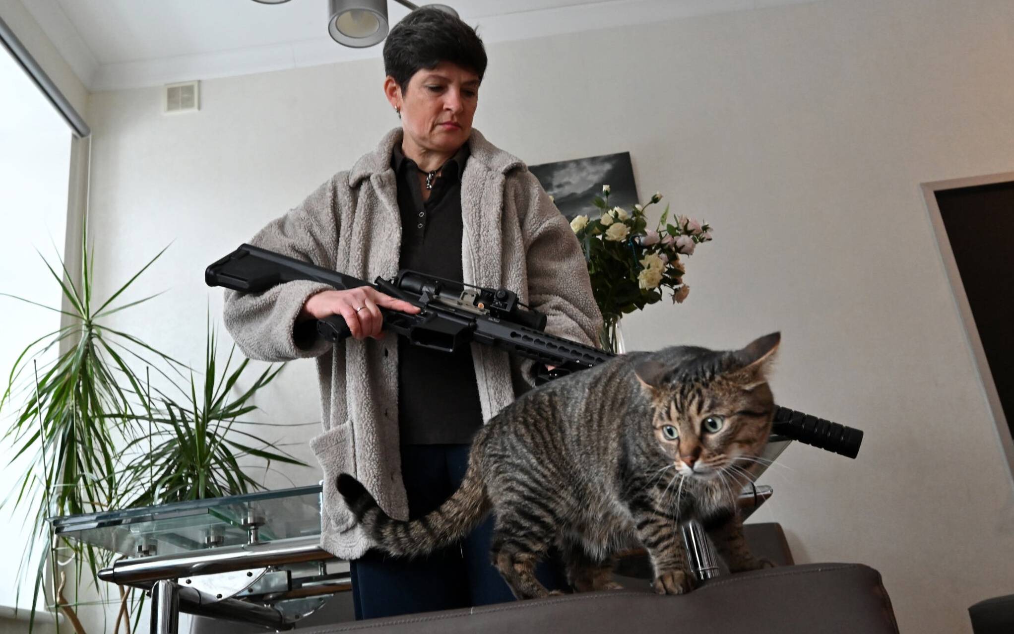 Mariana Jaglo, mother-of-three, talks on the phone as she holds her Ukrainian Z-15 - Zbroyar long rifle during an interview in the kitchen of her  flat in Kiev on January 28, 2022. - As fears grow of a potential invasion by Russian troops massed on Ukraine's border, this 52-year-old army reservist, insists in her willing to fight to defend her country. (Photo by Sergei SUPINSKY / AFP)