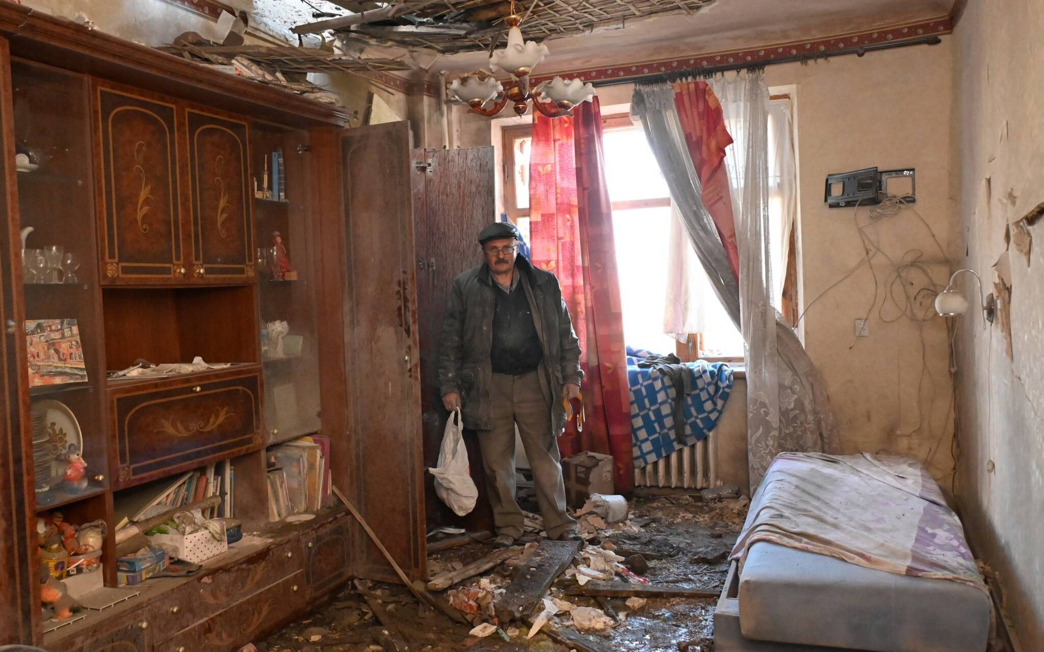 A man looks on his destroyed apartment in a residential building outskirts of Kharkiv on April 20, 2022. - More than five million Ukrainians have now fled their country following the Russian invasion, the United Nations says. (Photo by SERGEY BOBOK / AFP)