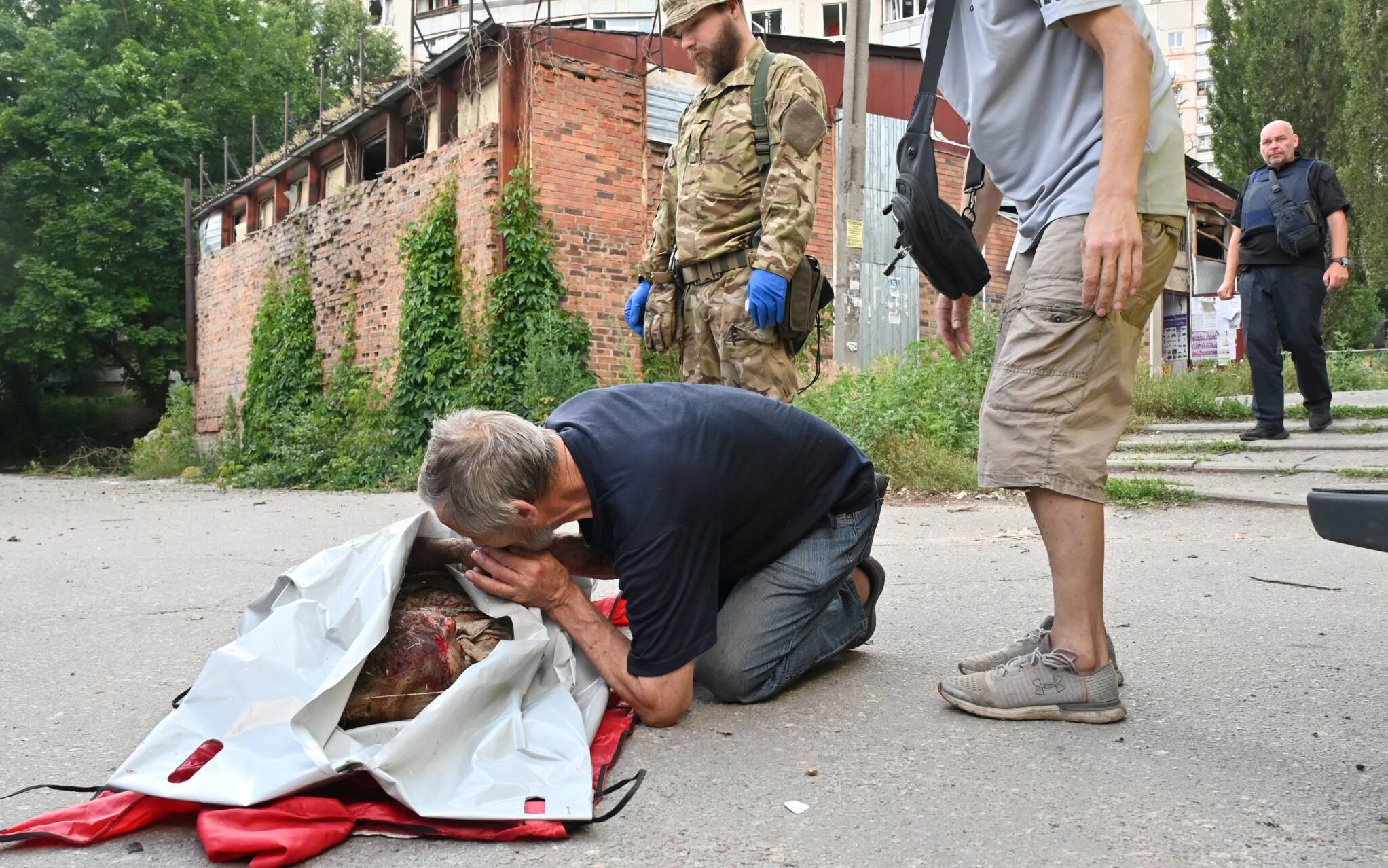 EDITORS NOTE: Graphic content / A mourns on the body of a local resident who died as a result of shelling by multiple launch rocket systems to a residential area in Kharkiv on July 7, 2022 amid the Russian invasion of Ukraine. - Three civilians were killed and 5 injured as a result of the shelling prosecutor's office of Kharkiv region said. (Photo by SERGEY BOBOK / AFP)