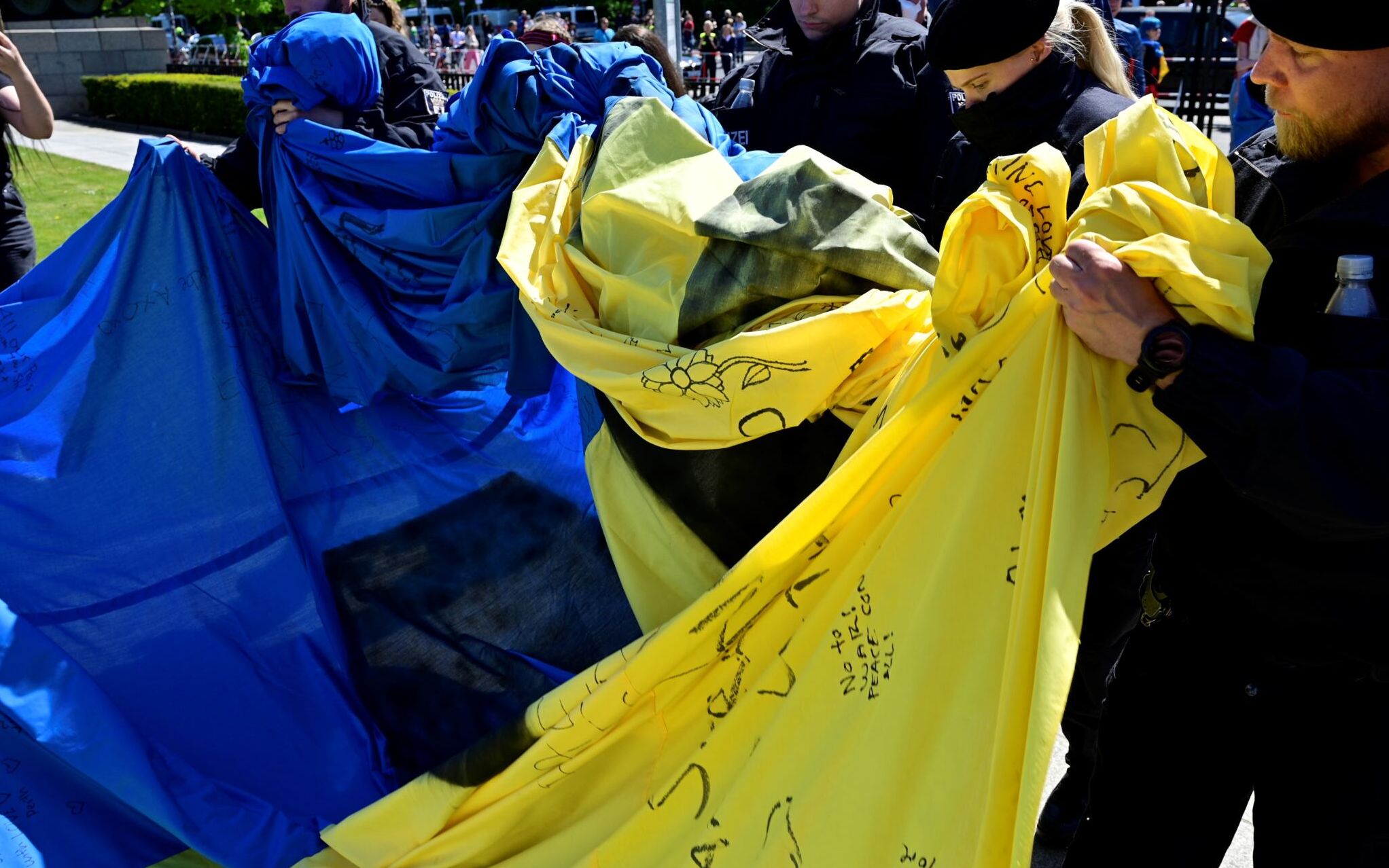 Police officers confiscate a giant Ukrainian flag that activists had unfurled at the Soviet War Memorial in Tiergarten in Berlin on May 8, 2022 during commemorations to mark the 77th anniversary of the 1945 victory against Nazi Germany. (Photo by John MACDOUGALL / AFP)