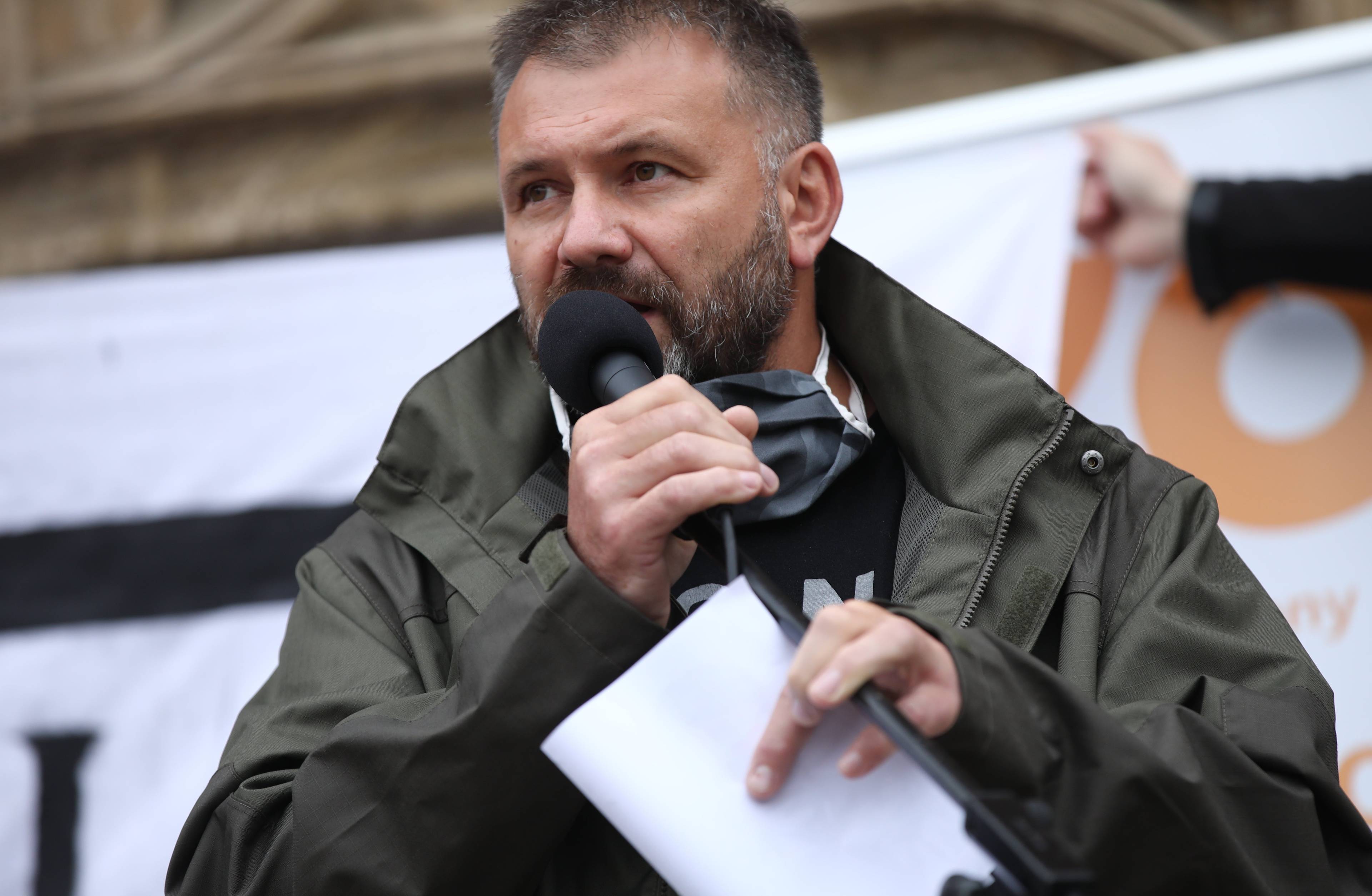 Mężczyzna stoi z mikrofonem w ręku, sędzia Waldemar Żurek