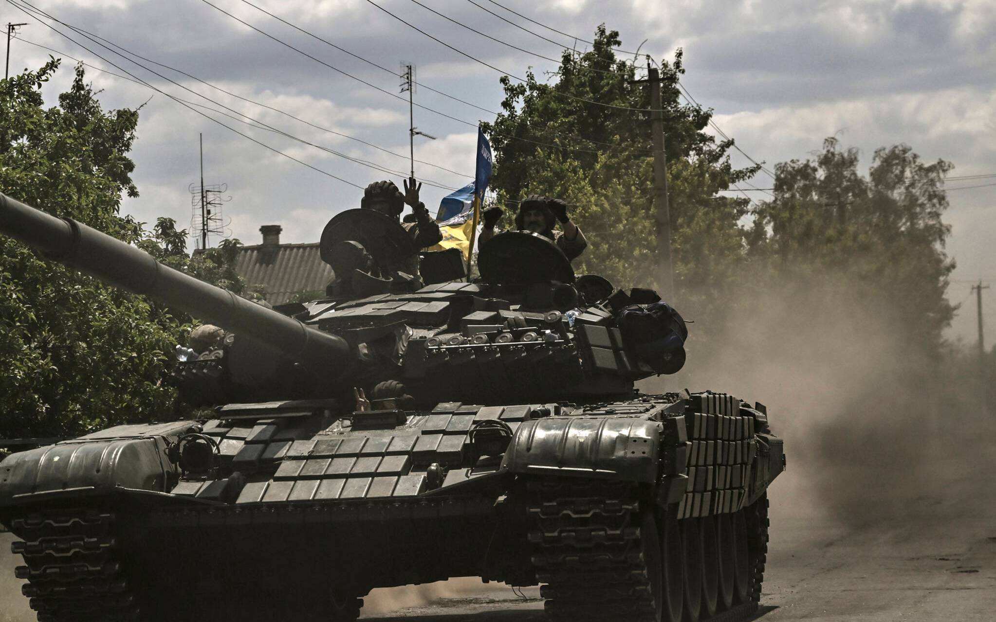 Ukrainian troop members move towards the front line with an army's Main Battle Tank (MBT) in the eastern Ukrainian region of Donbas on June 7, 2022. (Photo by ARIS MESSINIS / AFP)