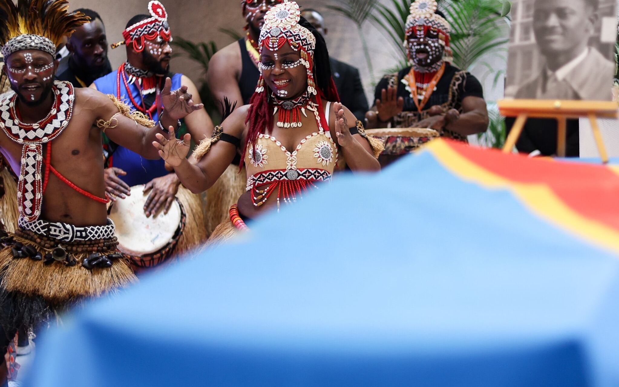 Dancers perform next to the coffin of Democratic Republic of Congo's first prime minister and independence hero Patrice Lumumba during a tribute ceremony at The Congolese Embassy before the departure of his last remains to DR Congo in Brussels on June 21, 2022. - The tribute takes place a day after an official ceremony to return the slain Congolese leader's tooth -- all that is left of the anti-colonialist icon who was murdered by Congolese separatists and Belgian mercenaries in 1961. (Photo by Kenzo TRIBOUILLARD / AFP)