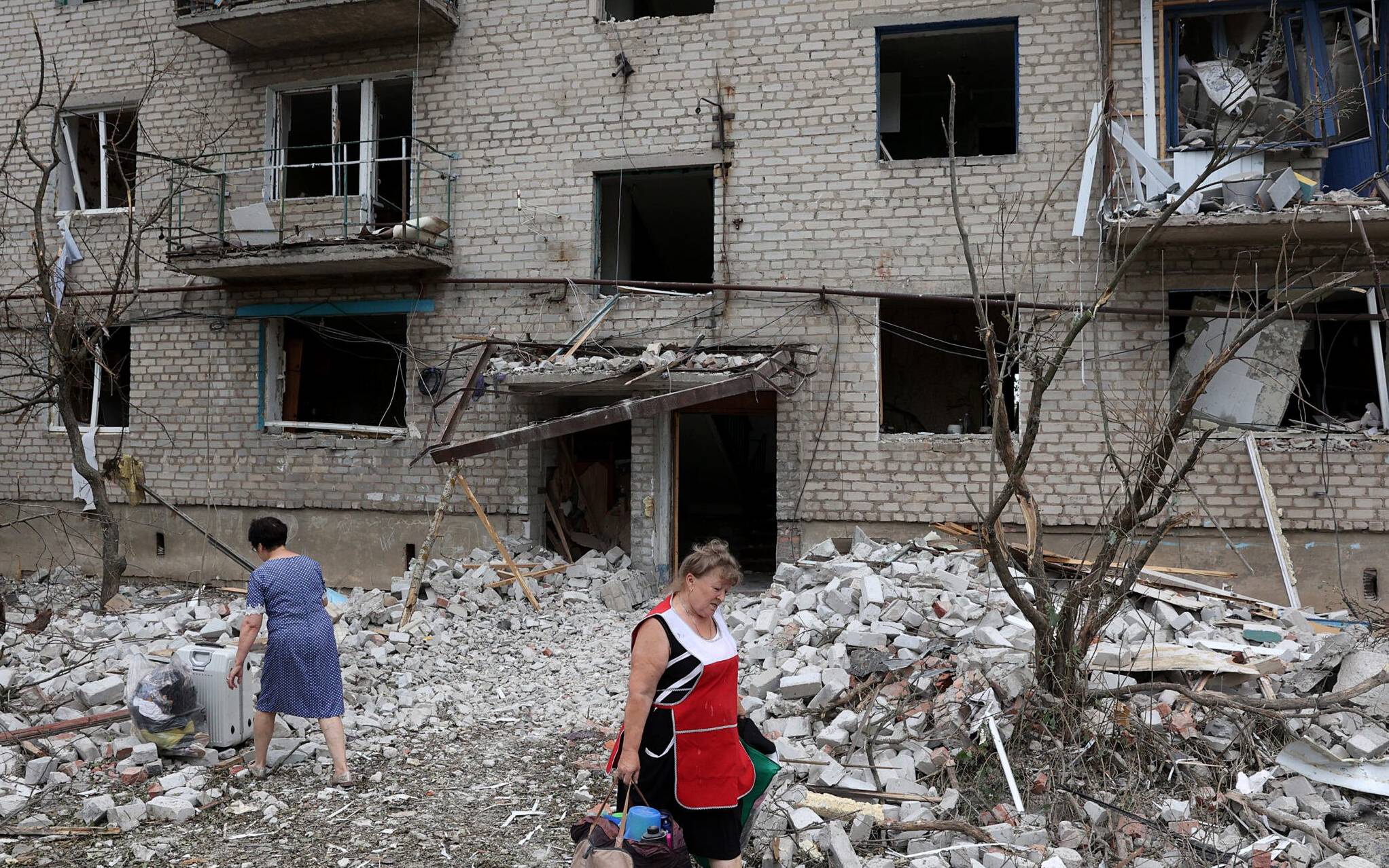 A local resident woman carries her belongings out of a building partially destroyed following shelling in Chasiv Yar, eastern Ukraine, on July 10, 2022. - The four-story building was hit by a Russian Hurricane missile, Pavlo Kyrylenko, governor of the Donetsk region that the Russian army is seeking to conquer, said on July 10, 2022 on Telegram. (Photo by Anatolii Stepanov / AFP)