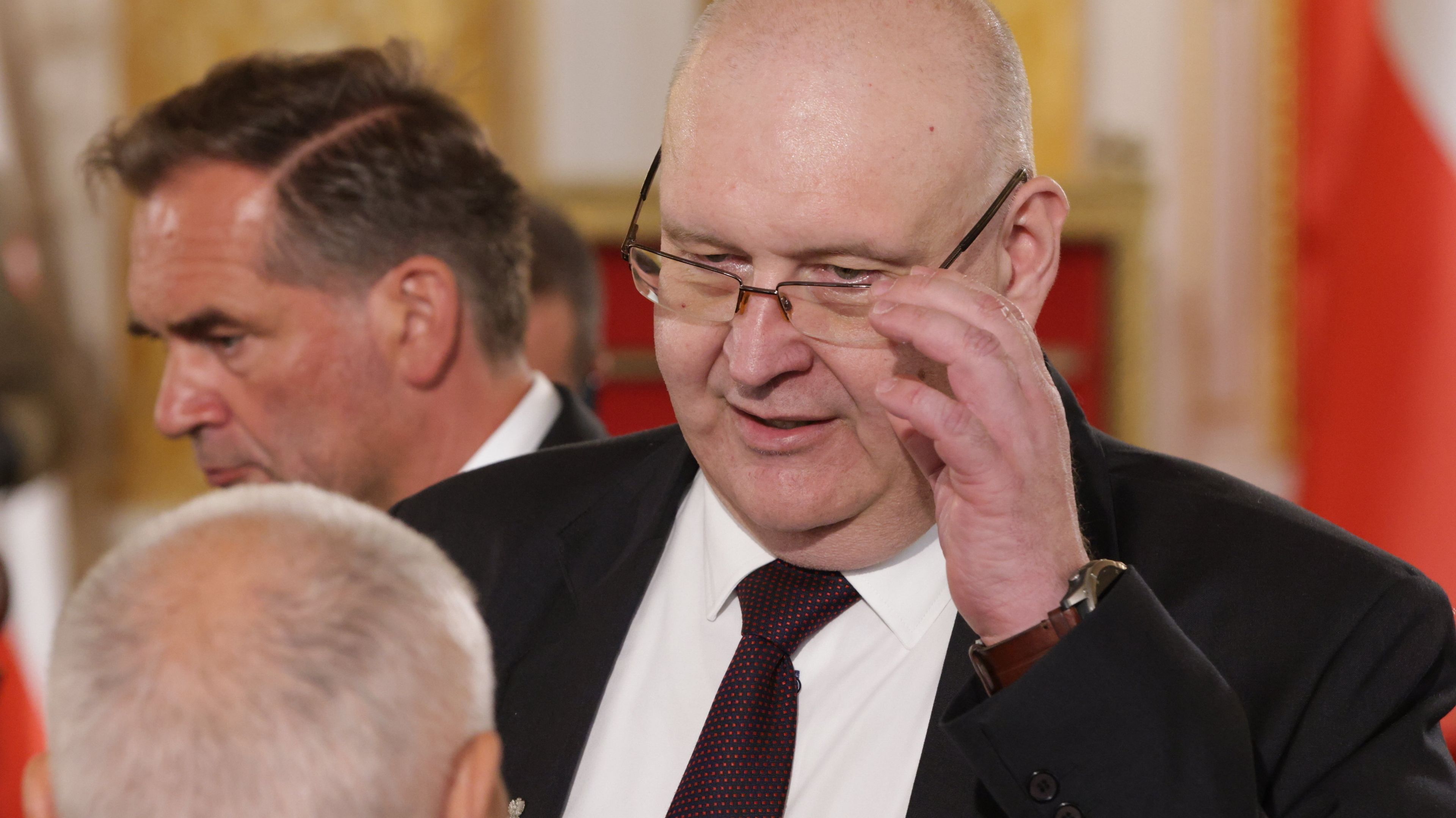 Starszy kompletnie łysy mężczyzna poprawia spadające okulary