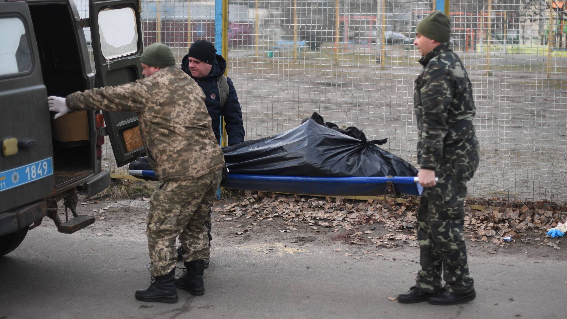 EDITORS NOTE: Graphic content / Ukrainian servicemen pick up the body of an Ukrainian man who was shot when a Russian armoured vehicle drove past him, on a sidewalk in the north of Kyiv on February 25, 2022. - Russian forces reached the outskirts of Kyiv on February 25, as Ukrainian President said the invading troops were targeting civilians and explosions could be heard in the besieged capital. (Photo by Daniel LEAL / AFP)