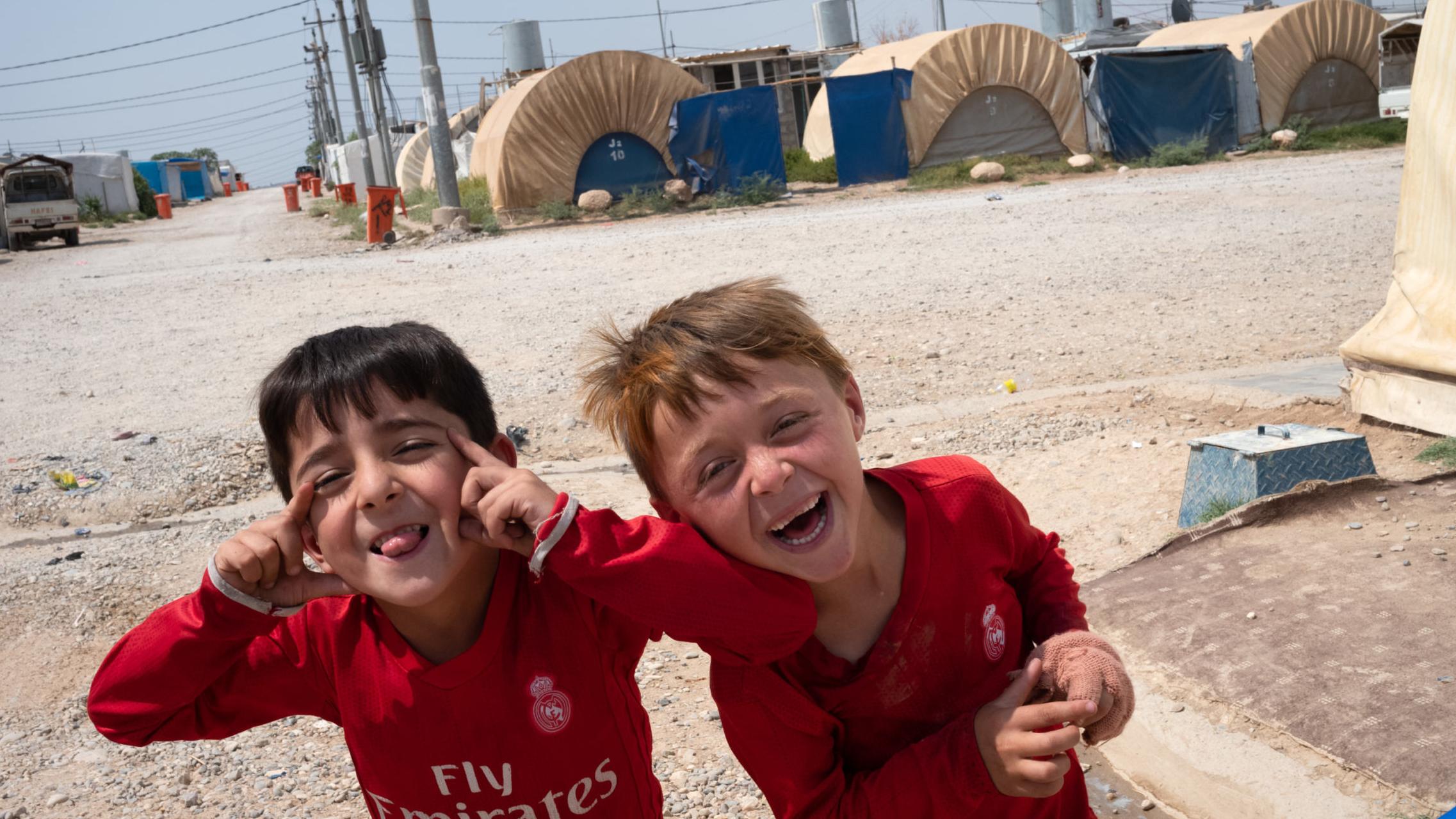 Chłopcy na tle obozu dla uchodźców w Iraku