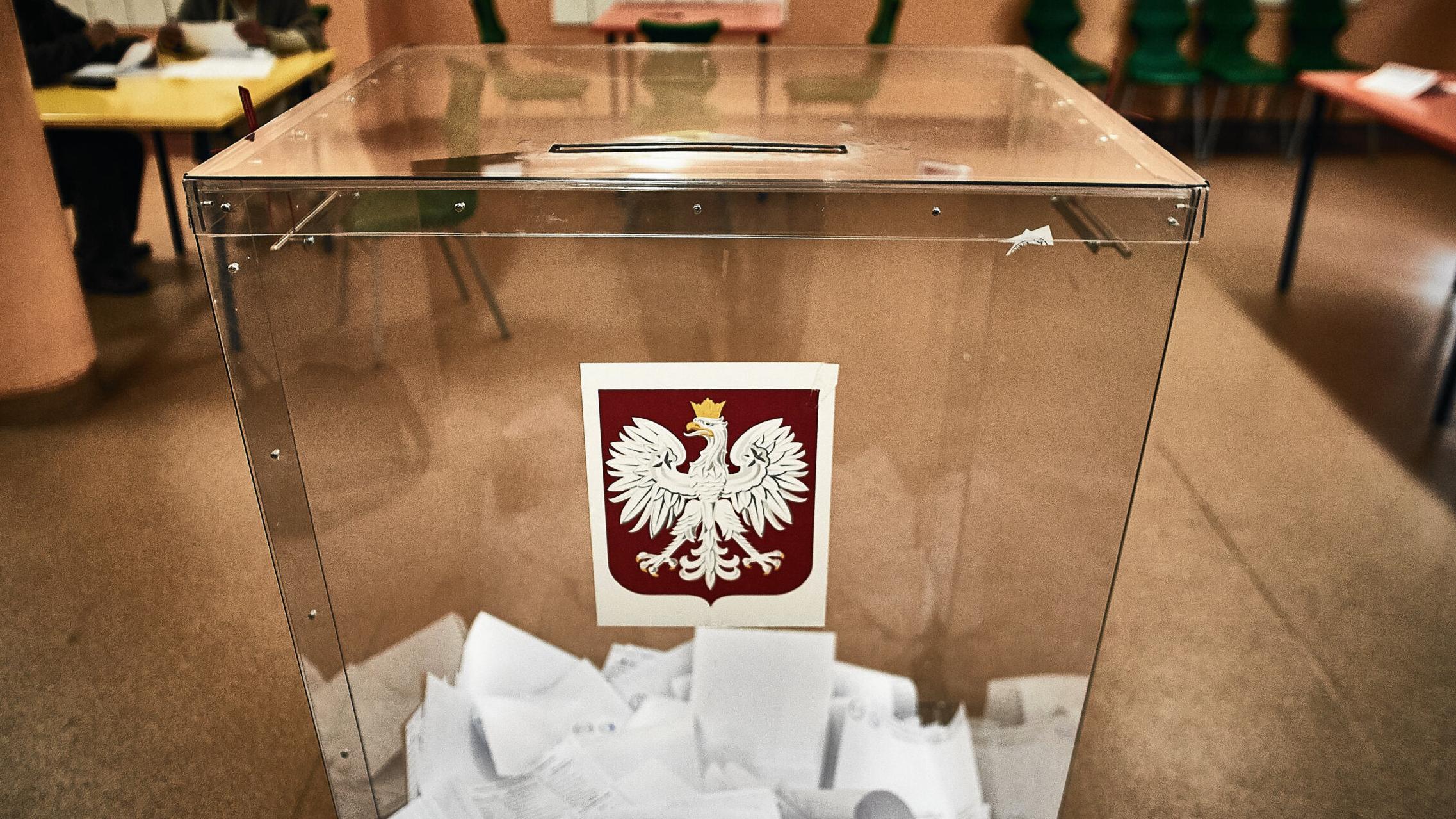Przezroczysta urna wyborcza wypełniona kartami do głosowania