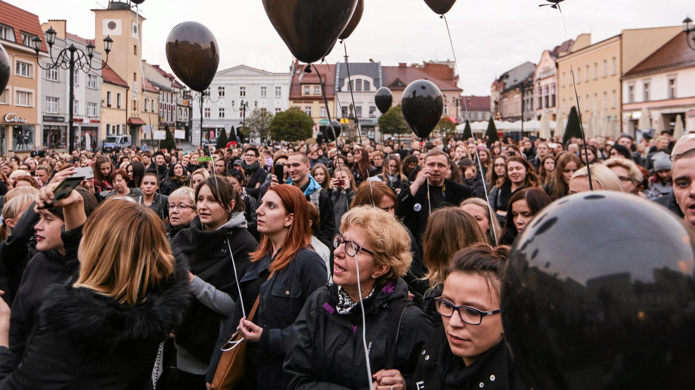 Kobiety zgromadzone na rynku trzymają czarne balony
