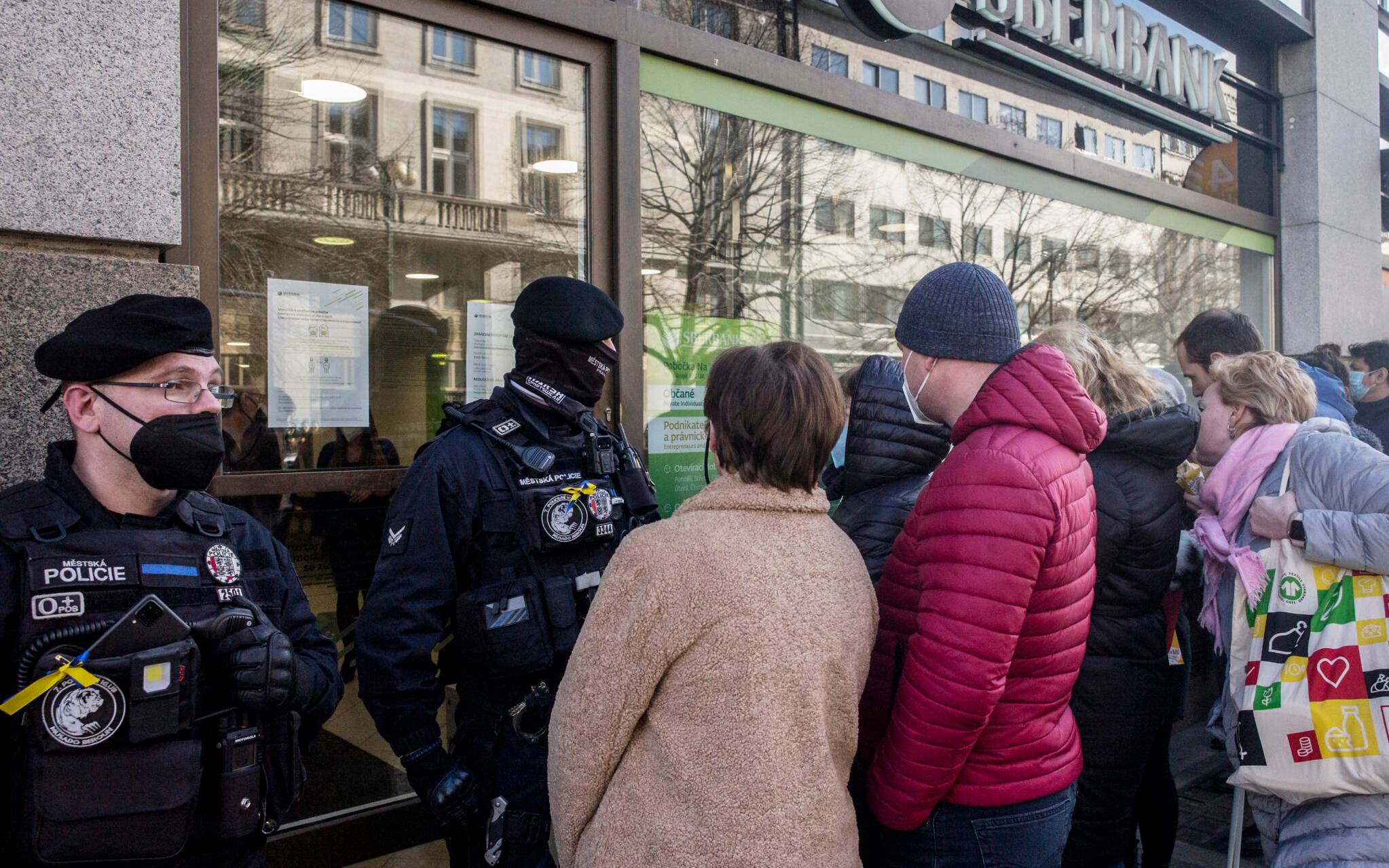 People queue outside a branch of Russian state-owned bank Sberbank to withdraw their savings and close their accounts in Prague on February 25, 2022, before Sberbank will close all its branches in the Czech Republic later in the day. - US President Biden was the first to announce sanctions, hours after Russian President Putin declared a "military operation" into Ukraine. The first tranche will hit four Russian banks -- including the country's two largest, Sberbank and VTB Bank -- cut off more than half of Russia's technology imports, and target several of the country's oligarchs. (Photo by Michal Cizek / AFP)