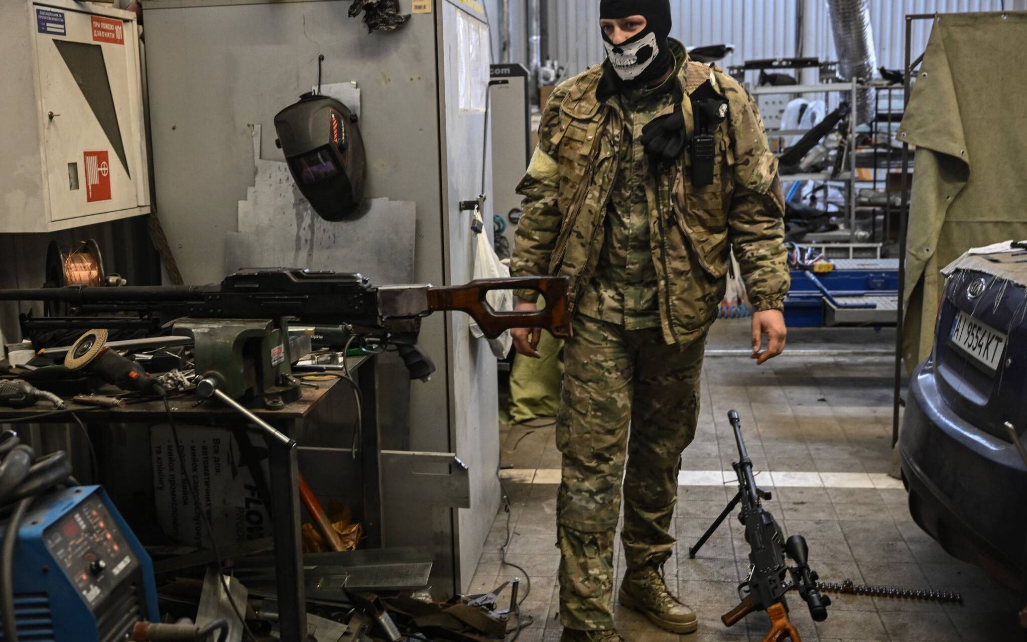 A volunteer stands inside an auto repair shop as he reconditions machine guns that were taken from the Russian army, in Kyiv on March 6, 2022. (Photo by ARIS MESSINIS / AFP)