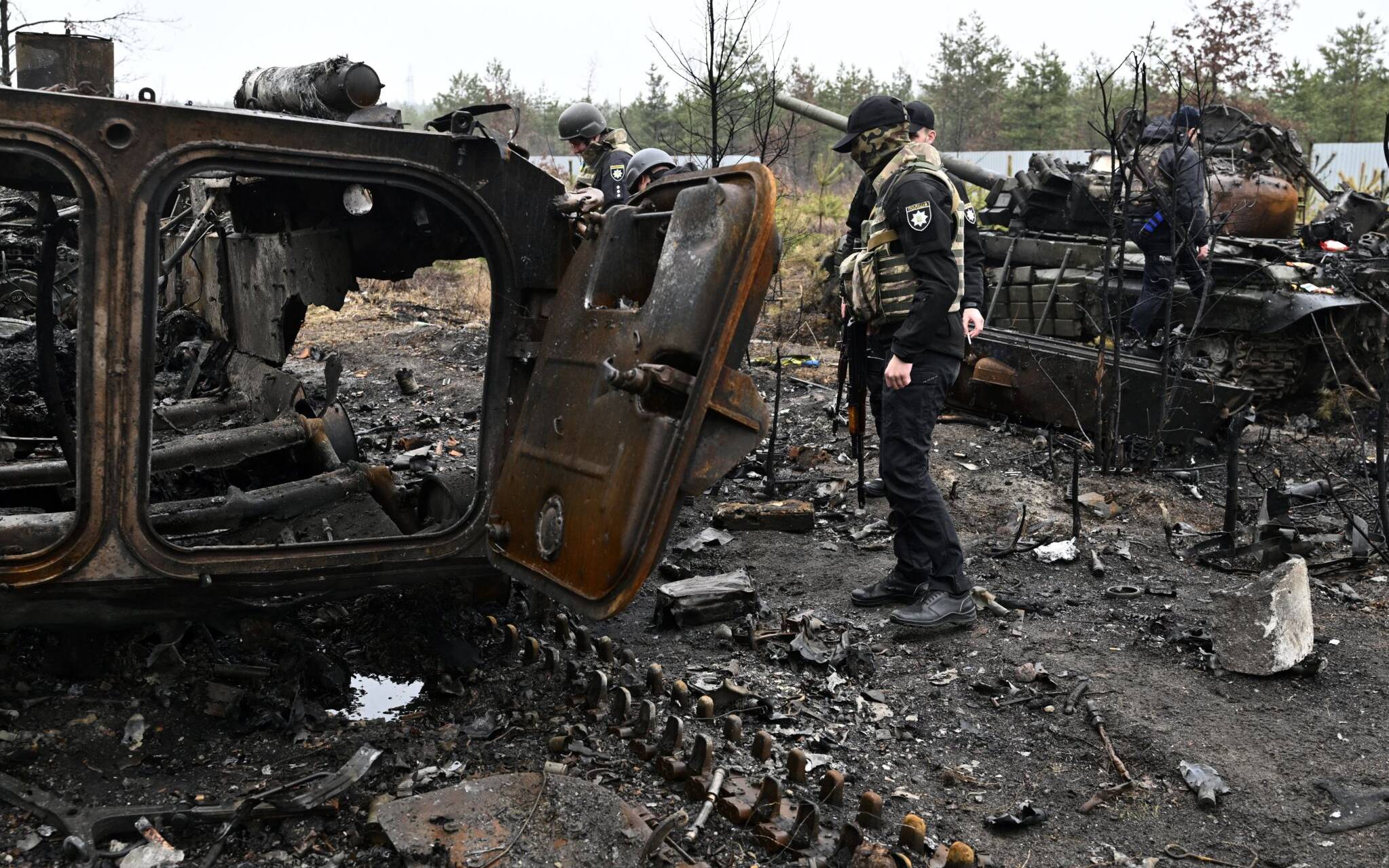 Ukrainian policemen check the wreckage of destroyed Russian tanks and armoured personnel carriers (APC) in Dmytrivka village, west of Kyiv, on April 2, 2022 as Ukraine says Russian forces are making a "rapid retreat" from northern areas around Kyiv and the city of Chernigiv. (Photo by Genya SAVILOV / AFP)